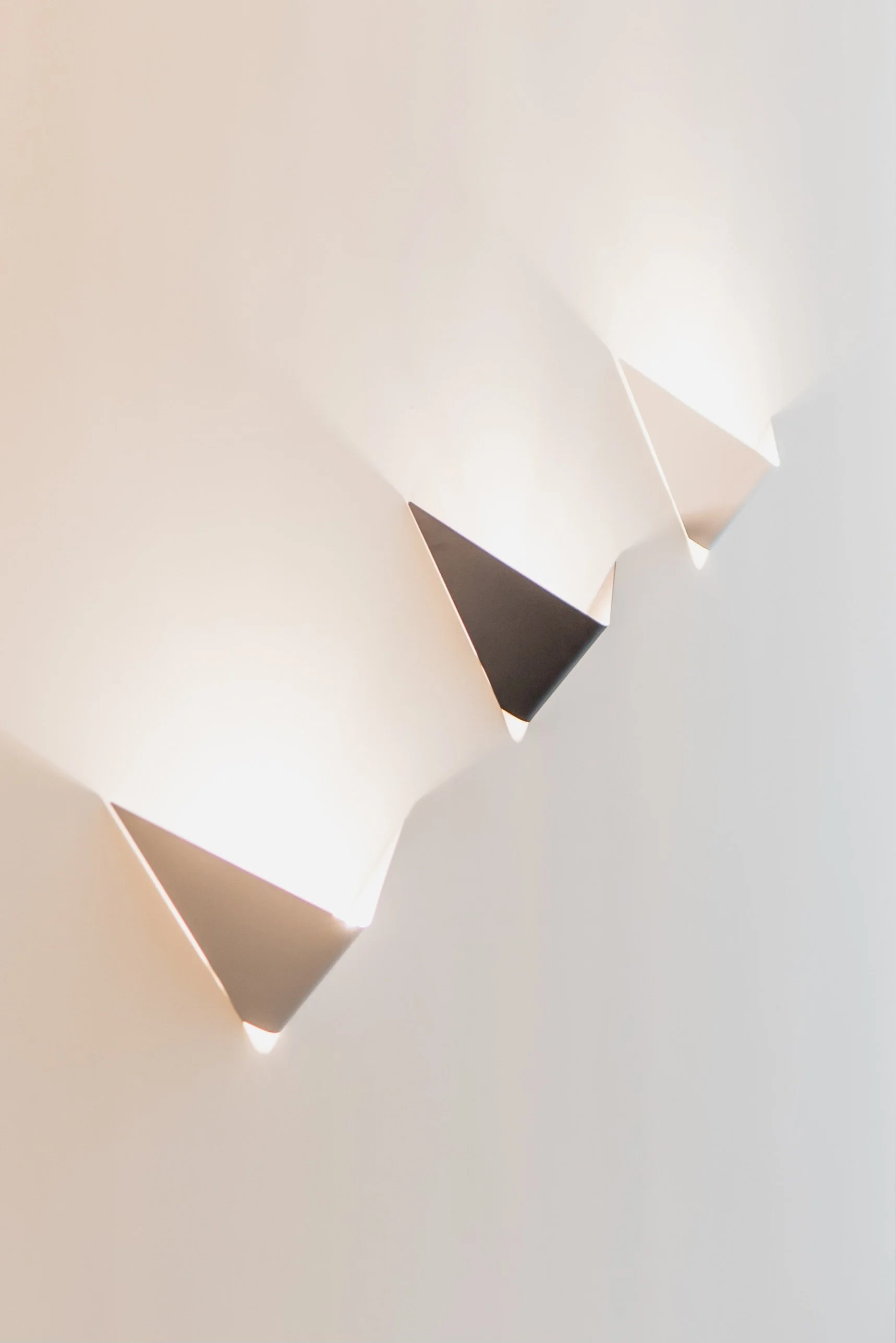 Close-up of a modern wall light fixture with geometric design, emitting soft white light.
