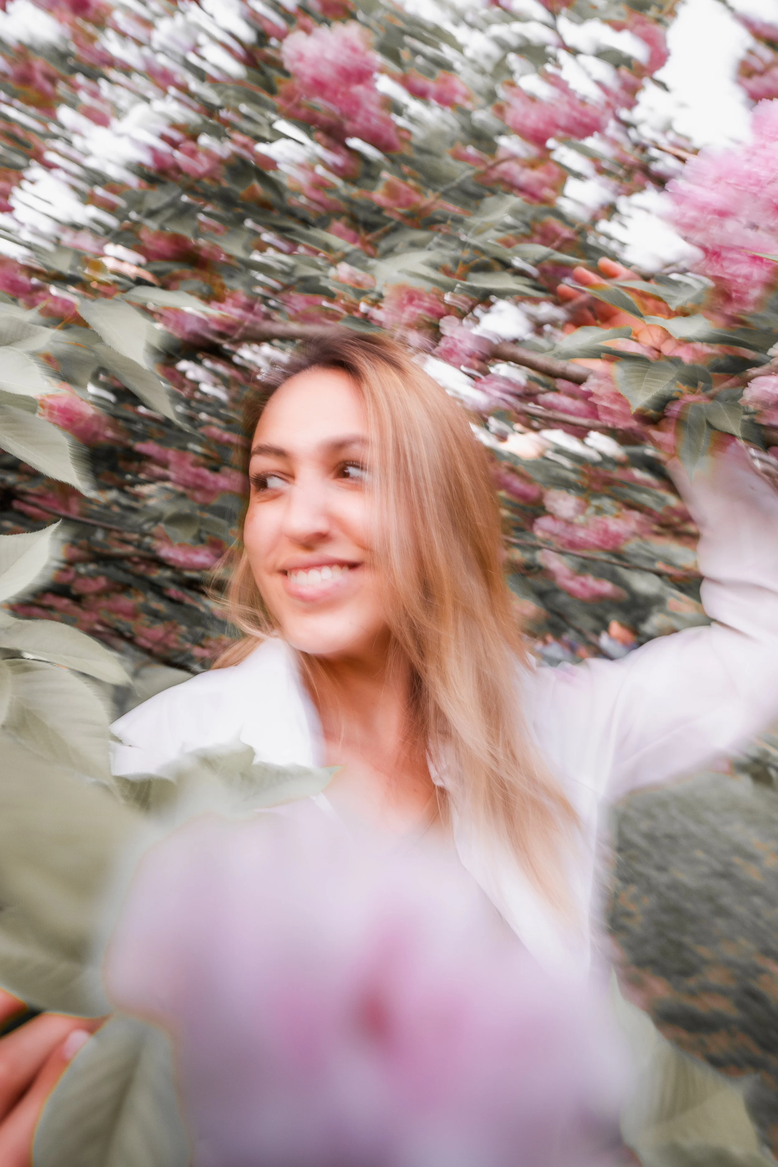 A woman smiling among pink and white flowering cotton plants.