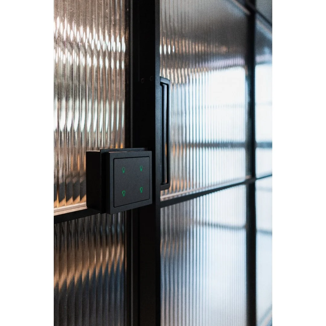Close-up of an electronic access control panel with four green indicator lights, mounted on a metallic textured door or wall.