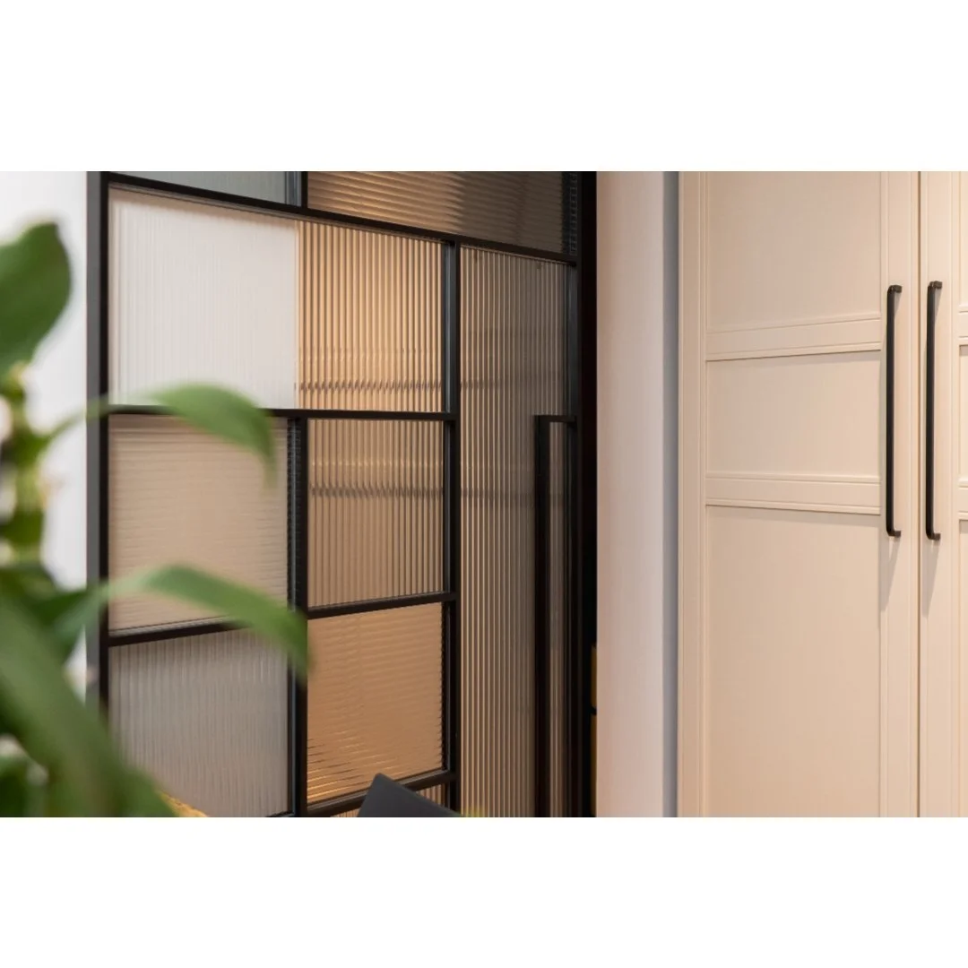 Close-up of kitchen cabinets with black handles next to a textured glass partition.