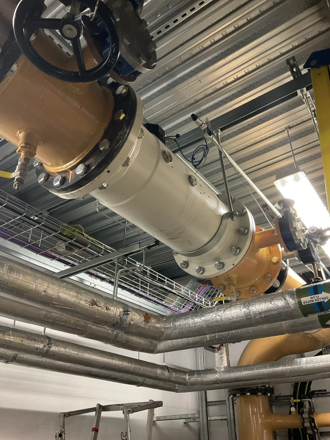 Close-up view of industrial pipes and large valves in a mechanical room.