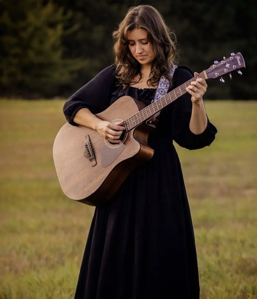 A singer song writer in a grassy field