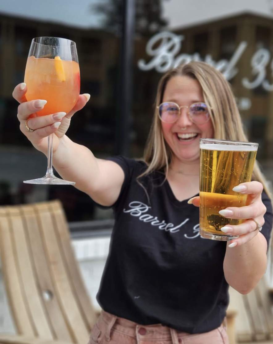 A happy woman serving wine and beer in a Barrel 33 t-shirt