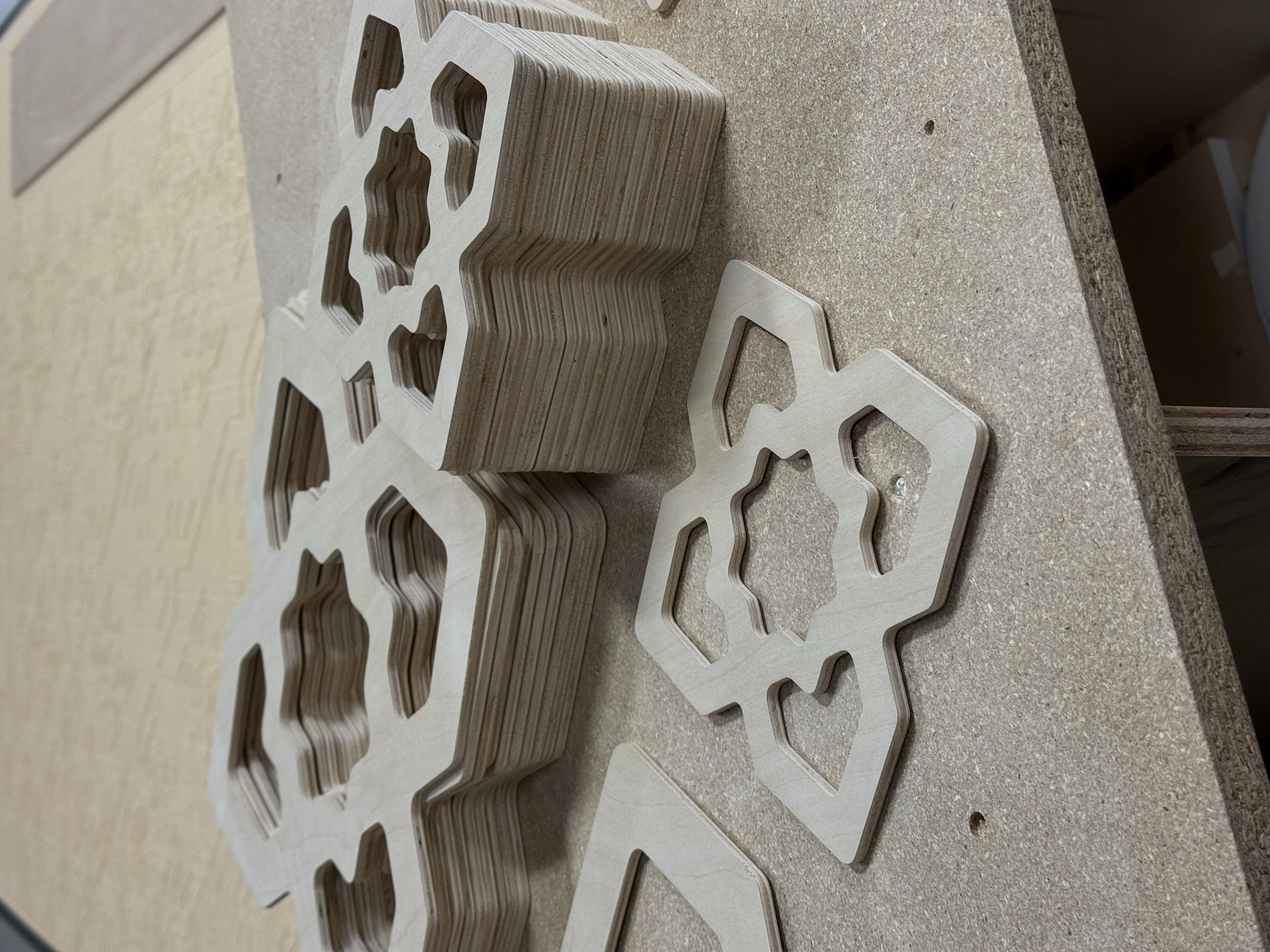 Stacked snowflake-shaped wooden pieces and some loose pieces on a workbench.