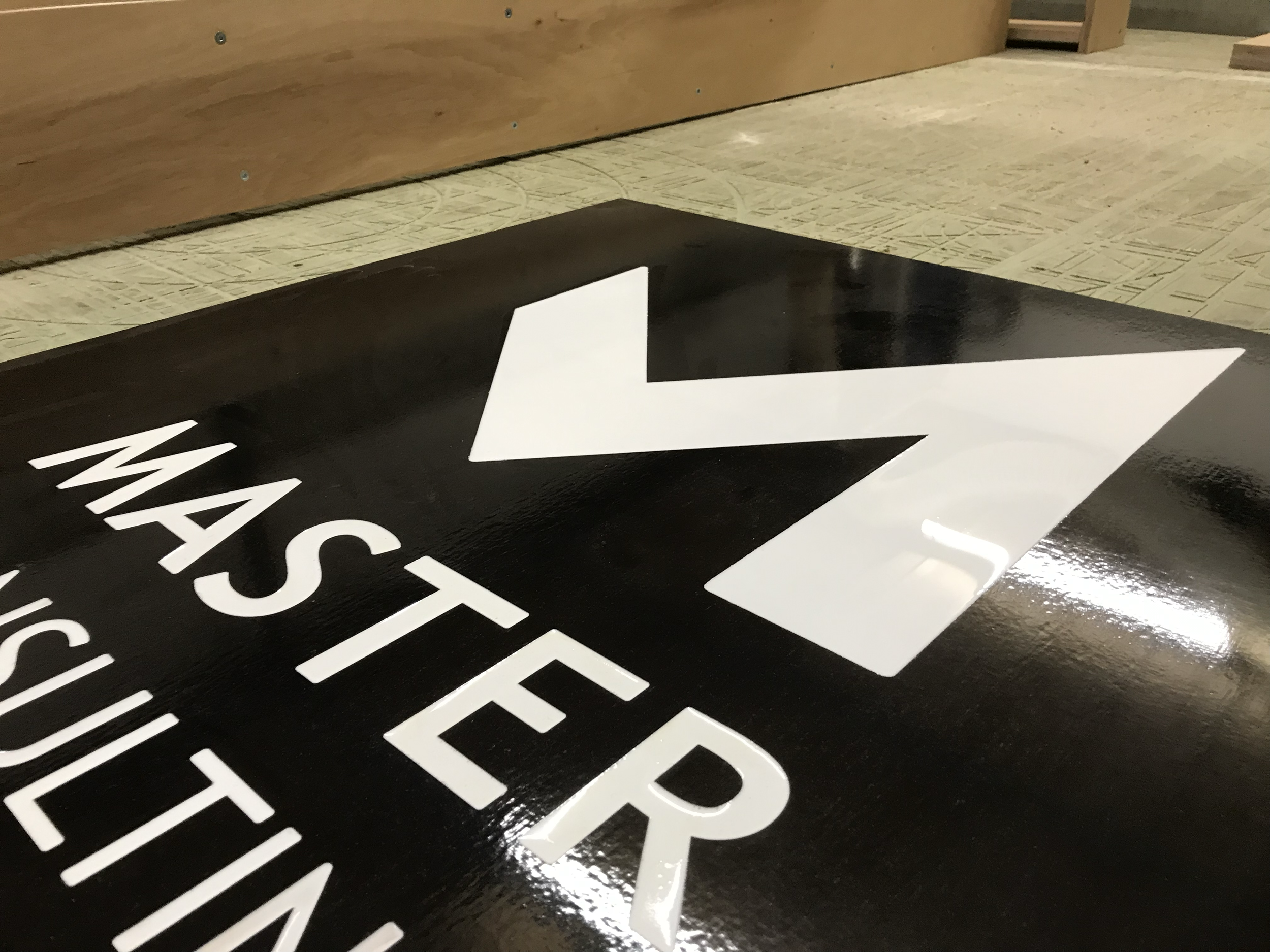 Black sign with a white arrow pointing to the right, the sign has the text 'MASTER' and other partially visible words.