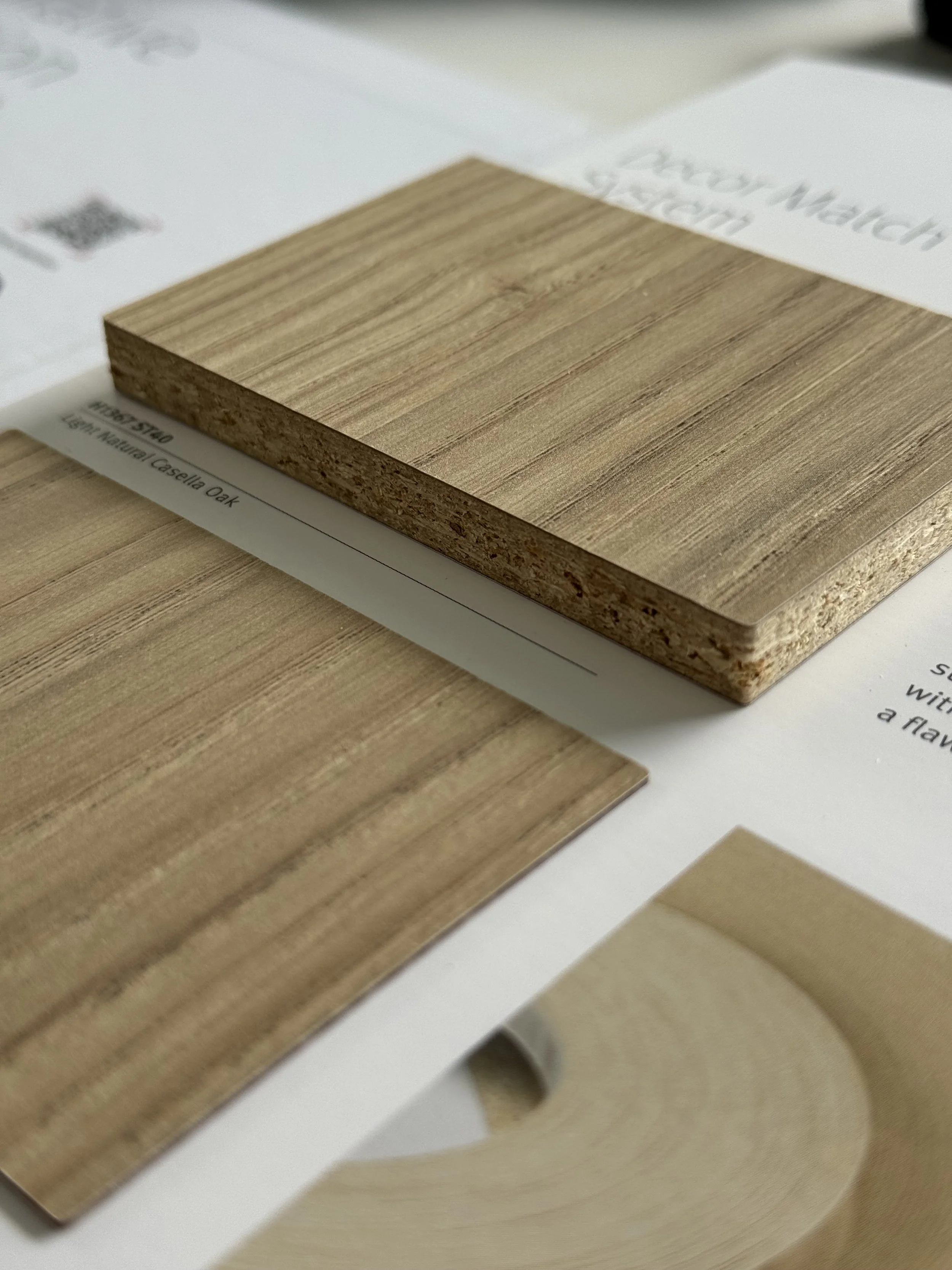 Close-up of a sample wood laminate called Light Natural Casella Oak on a white marketing display.