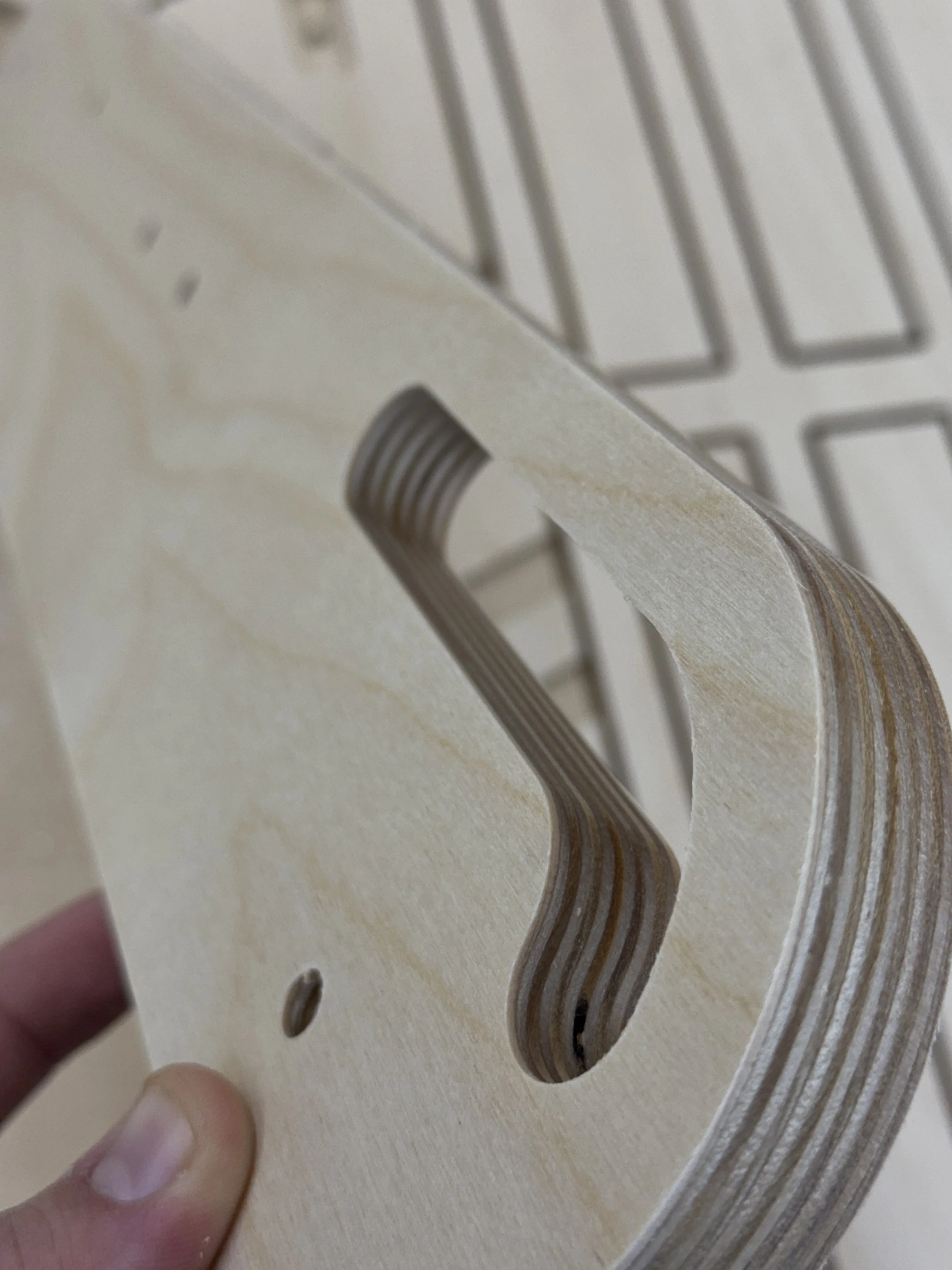 Close-up of a wooden piece with a screw hole and a rectangular cut-out, held by a person's hand.