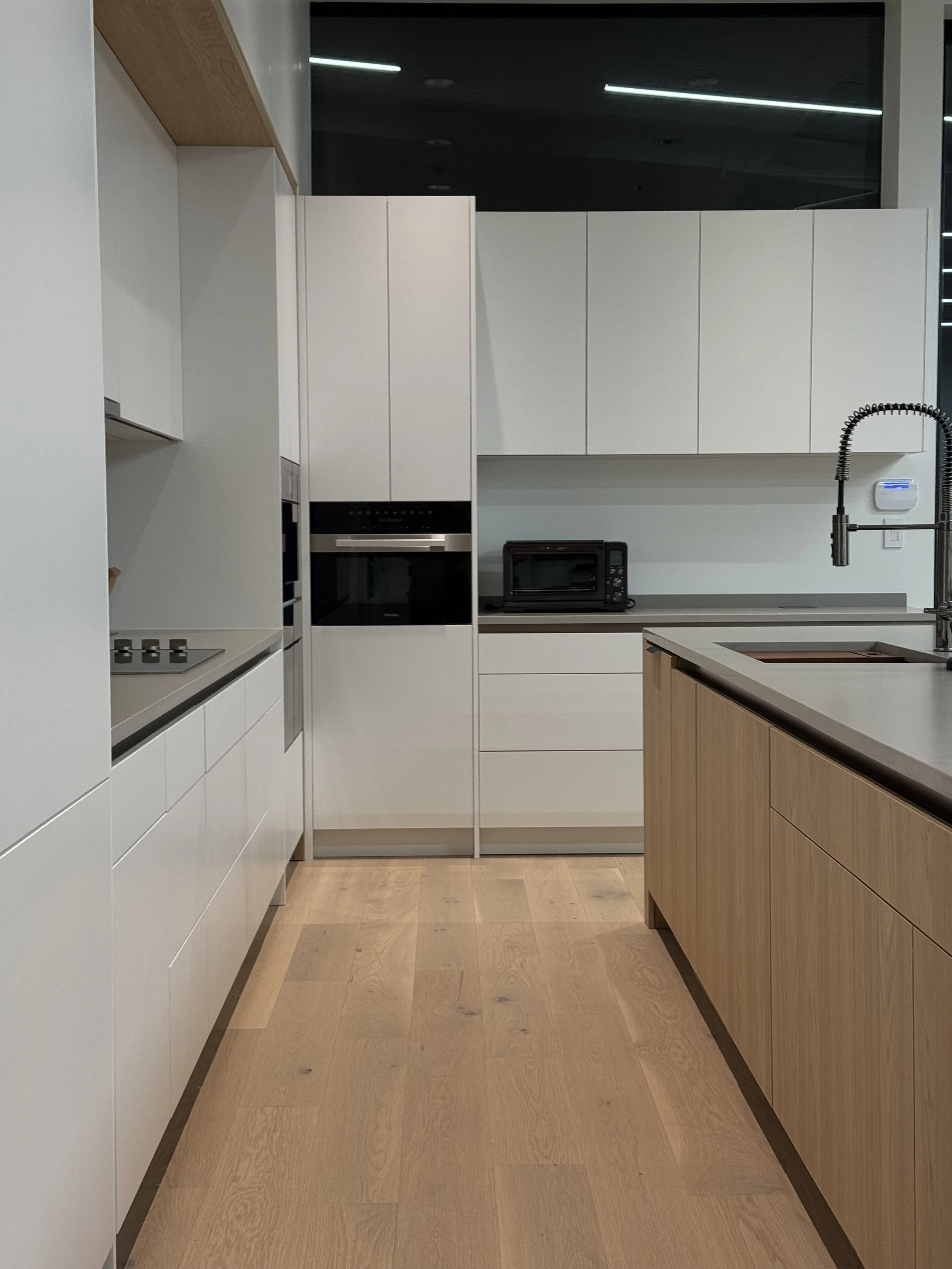 Modern kitchen with white cabinets, black appliances, a wooden island, and light hardwood floors.