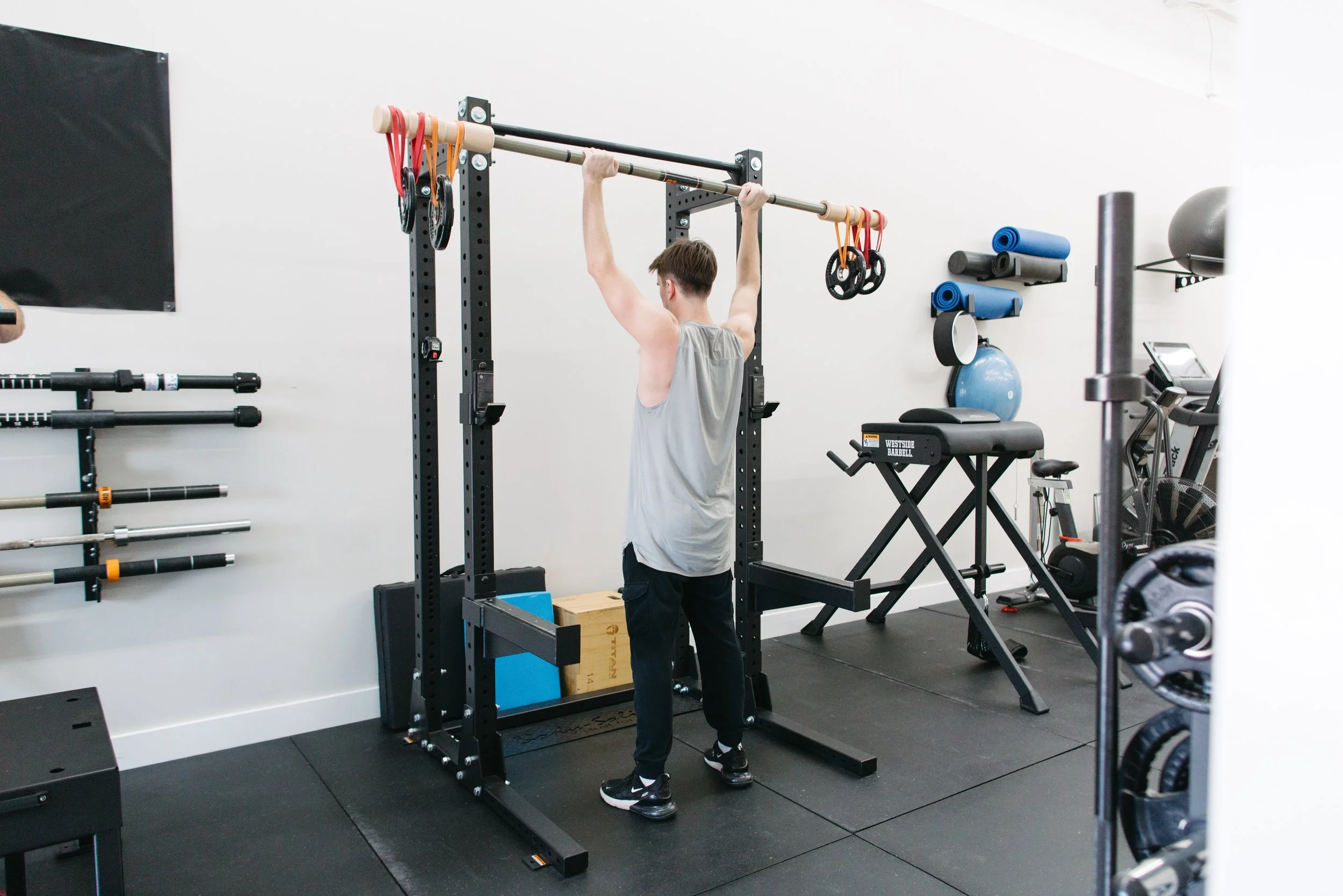 Client performing overhead press on a bamboo bar at CoGym studio