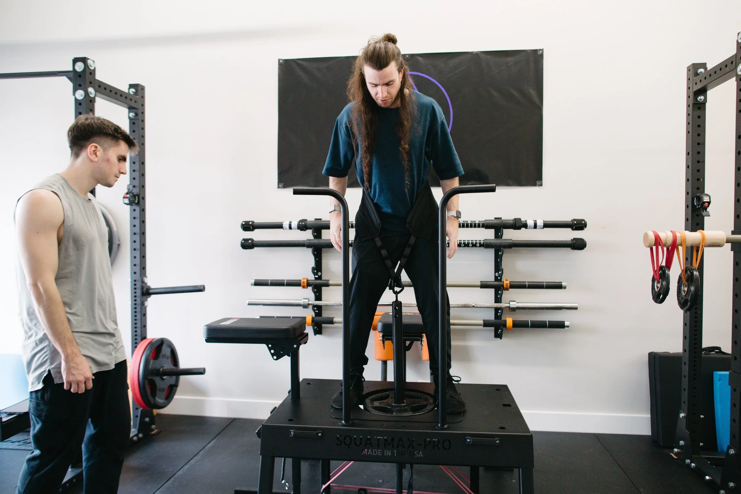 CoGym coach demonstrating belt squat technique during coached workout