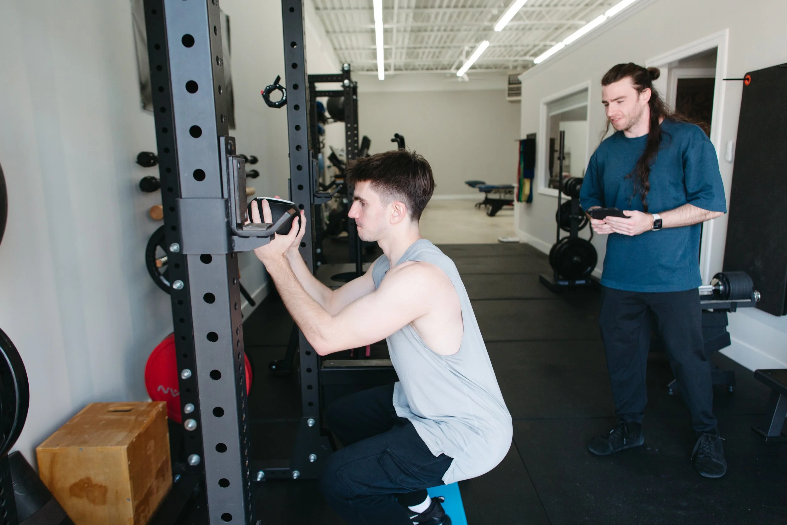 Client performing barbell squat under coach supervision at CoGym
