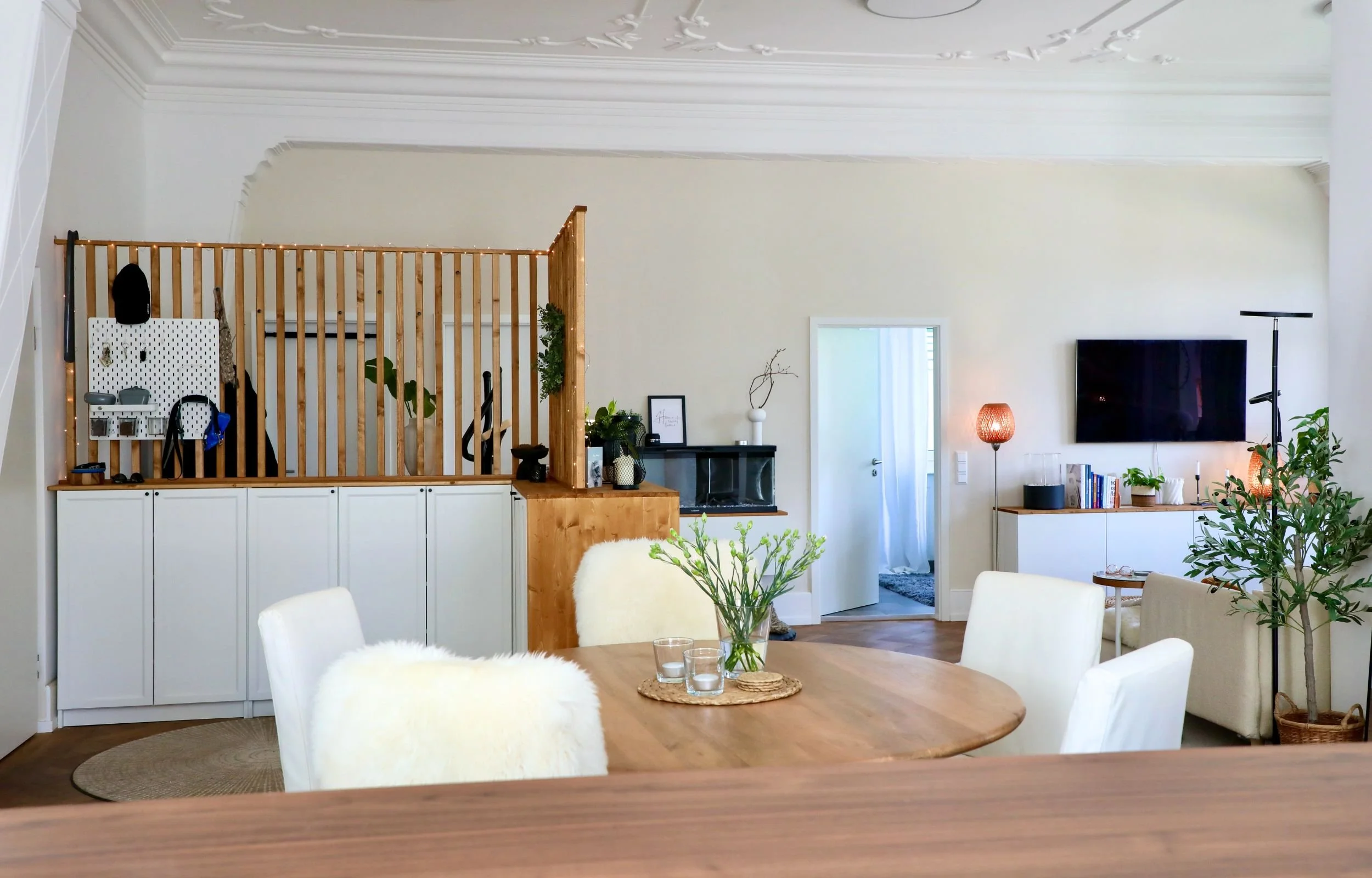 Altbau-Wohnzimmer mit Raumteiler, creme Wand und hohen Stuckdecken