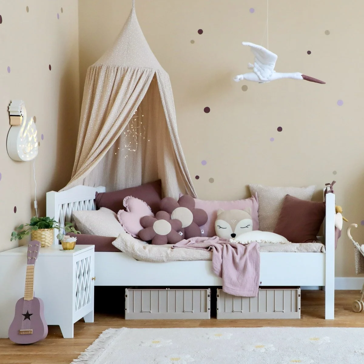 Weißes Kinderbett mit weichen Textilien in beige und Lila