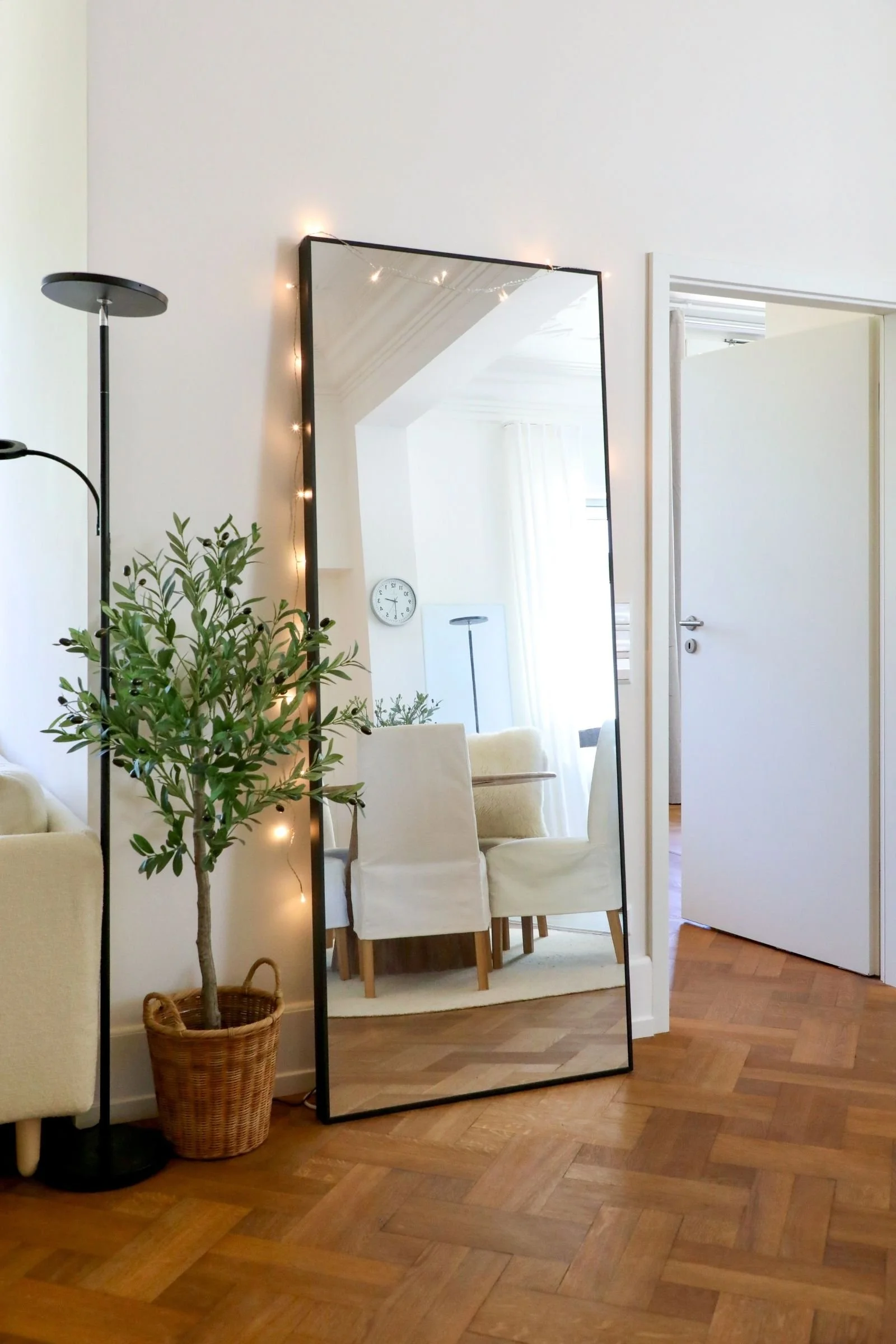 Großer Bodenspiegel vor einer weißen Wand mit Pflanze, Lampe und Eichenparkett