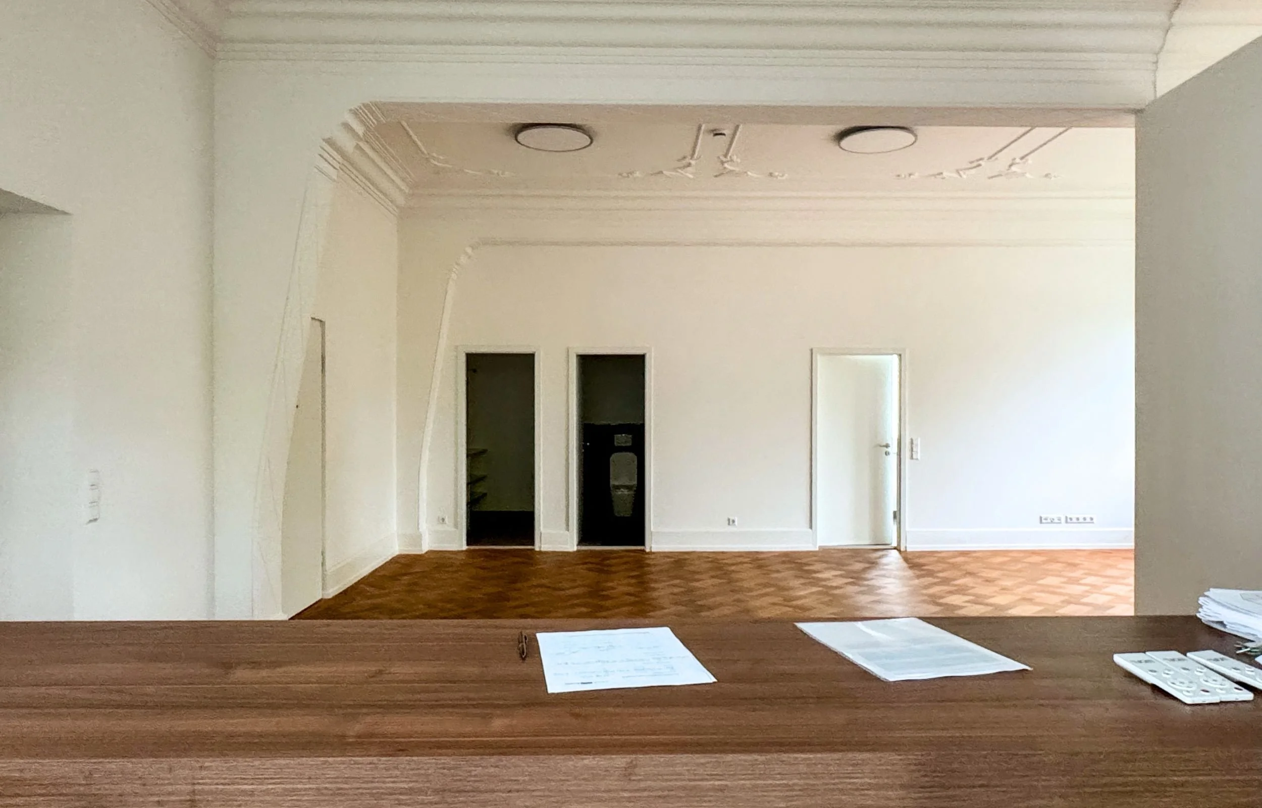 Leere Wohnung mit Stuckdecken, weißen Wänden und Eichenparkett