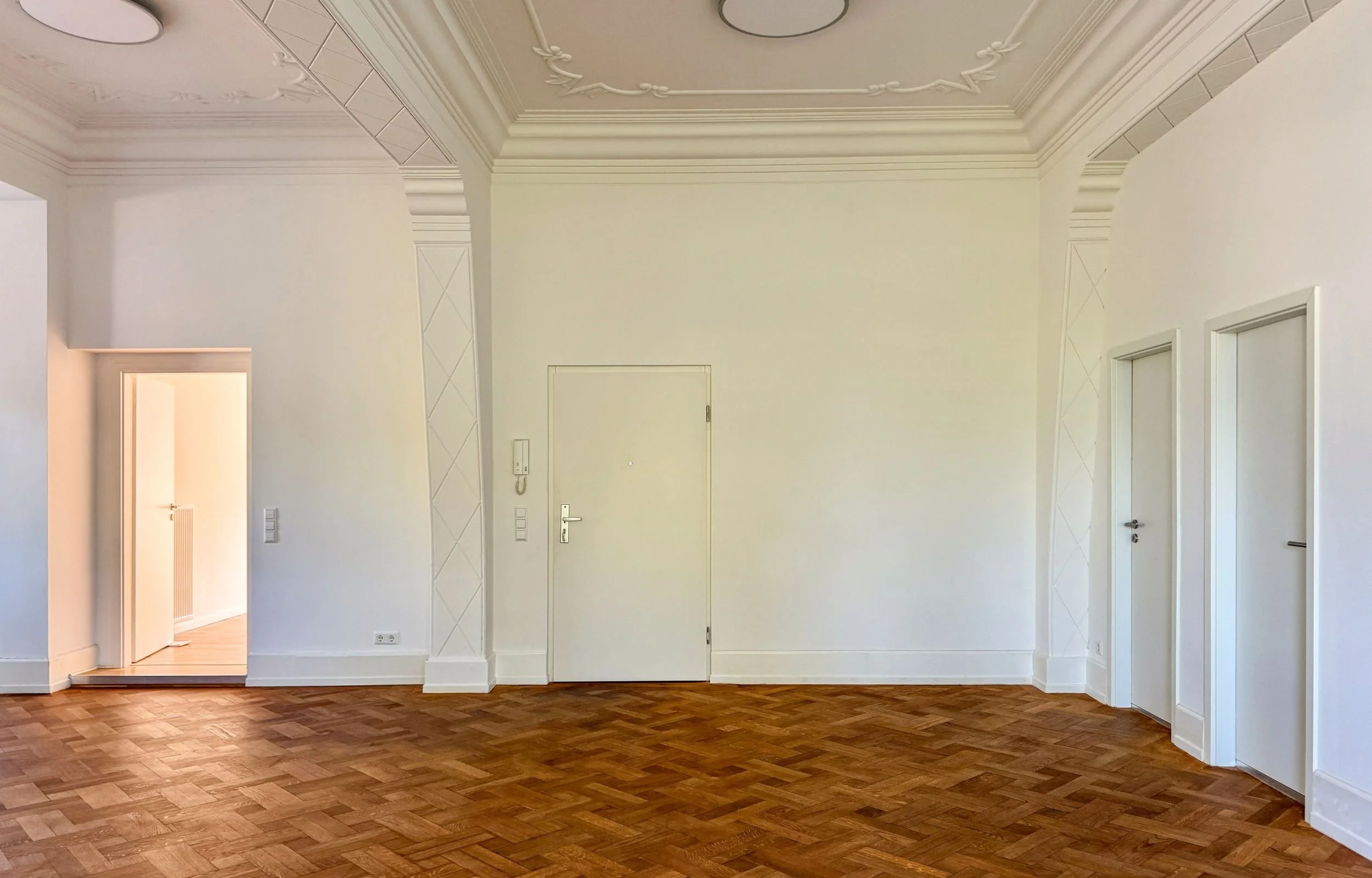 Altbau-Wohnung mit weißen Wänden, Türen und Stuckdecken