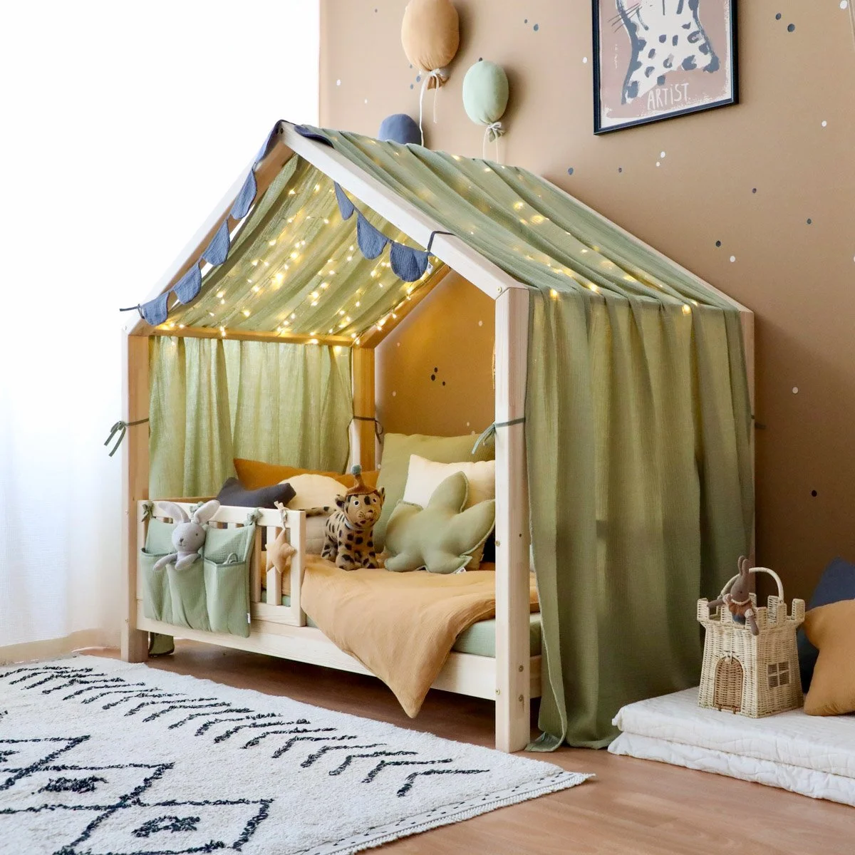 Hausbett an brauner Wand mit grünem Betthimmel und Kissen