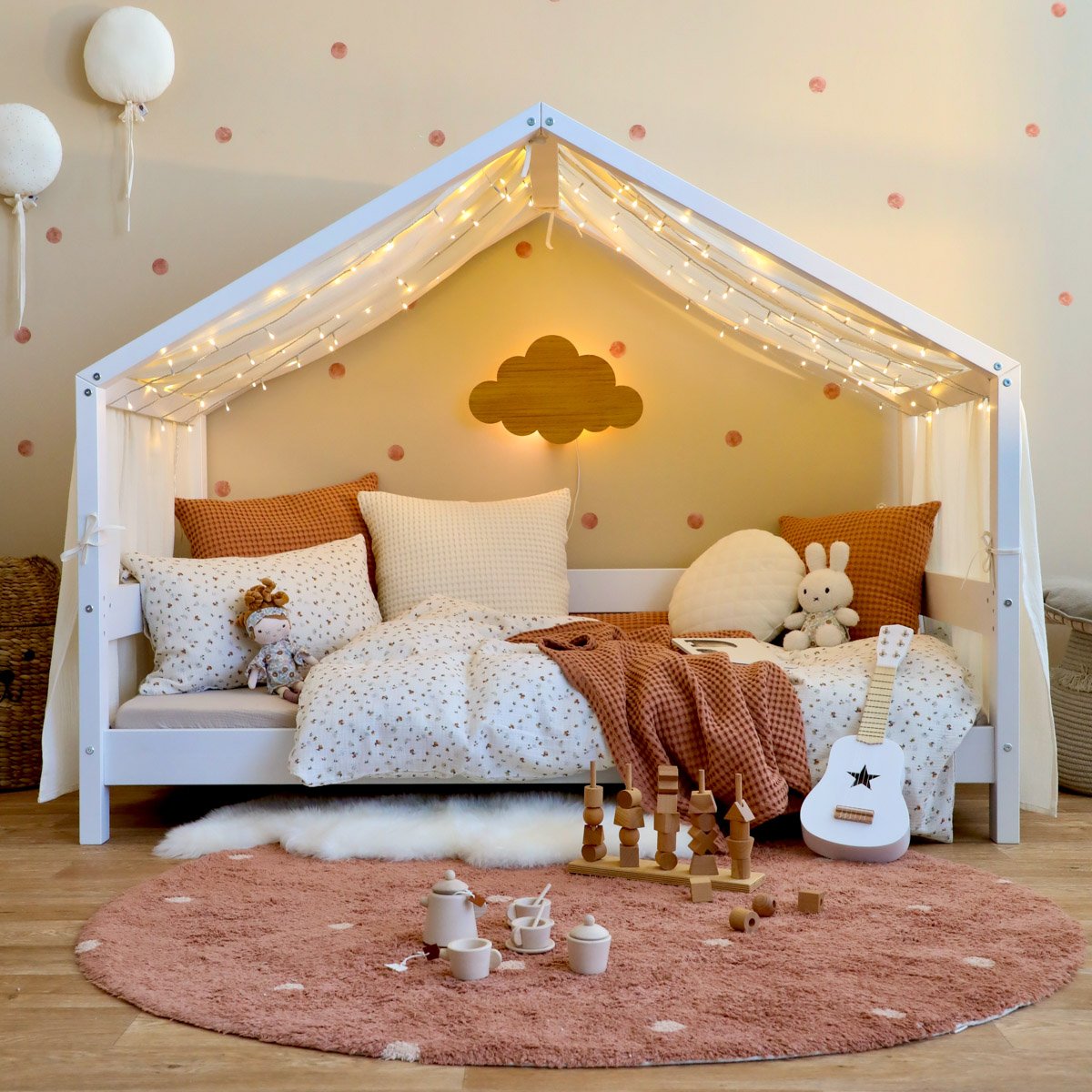 Hausbett mit weichem Himmel, Bettwäsche, Teppich und Lammfell im gemütlichen Kinderzimmer