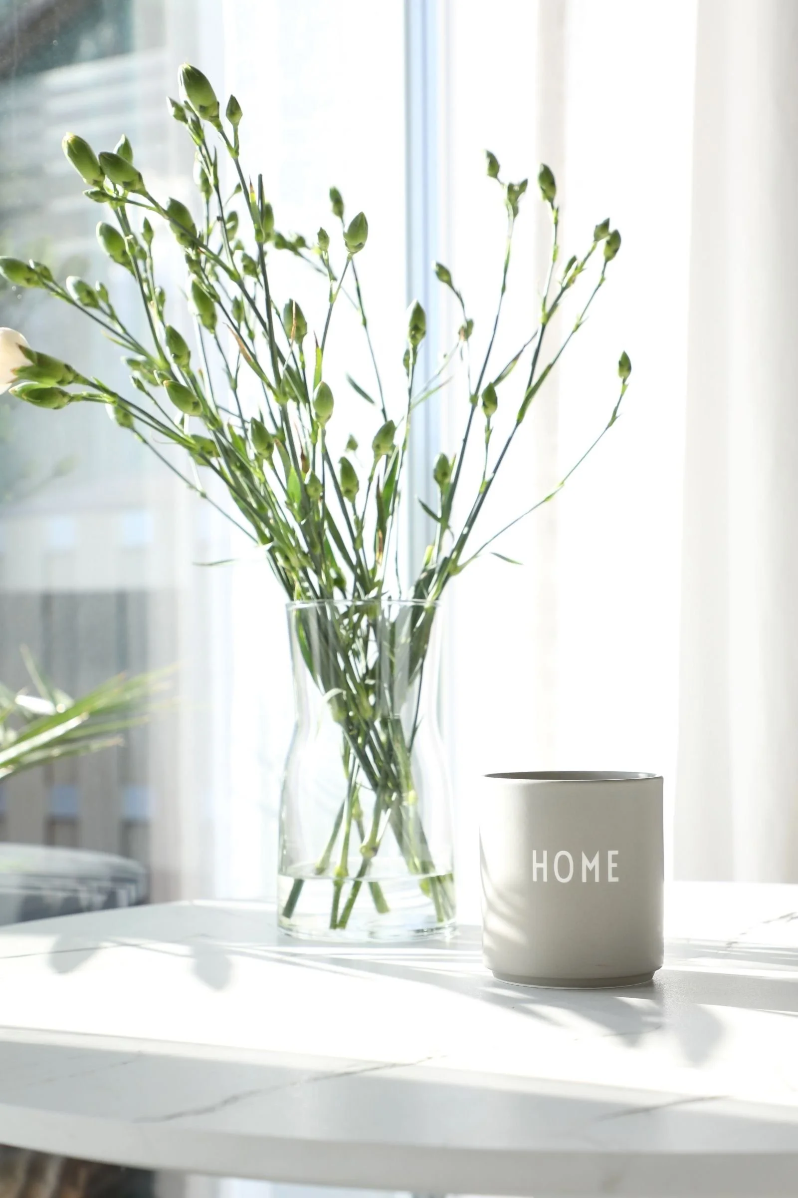Blumenvase aus Glas mit Nelken und Keramik-Windlicht