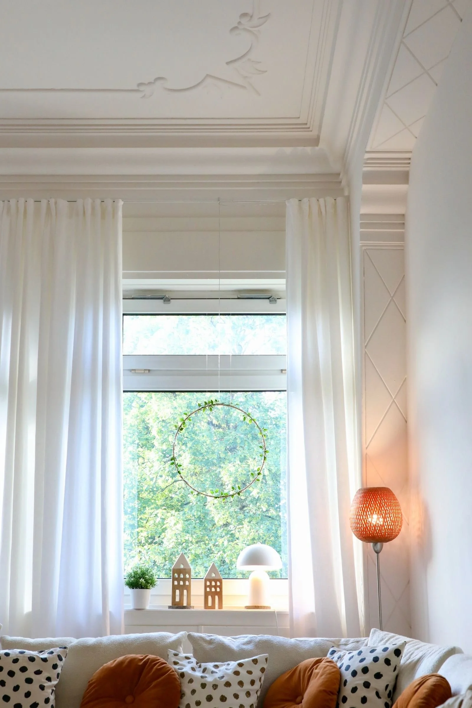 Fenster mit Lampen, Deko, Stuckdecken und Kissen auf dem Sofa