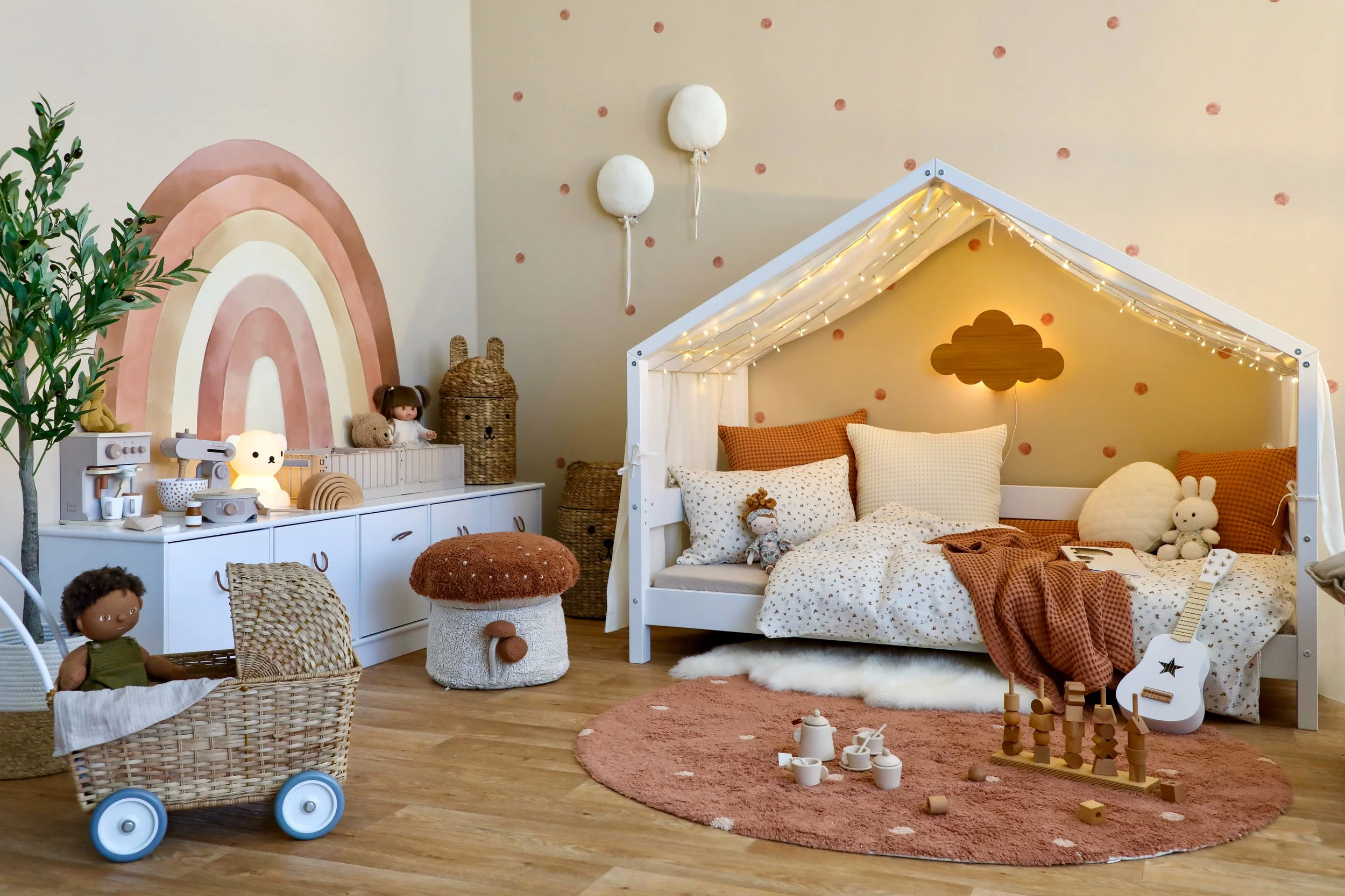 Gemütliches Kinderzimmer in warmen Farben mit Hausbett, Regenbogen an der Wand und Holzspielzeug
