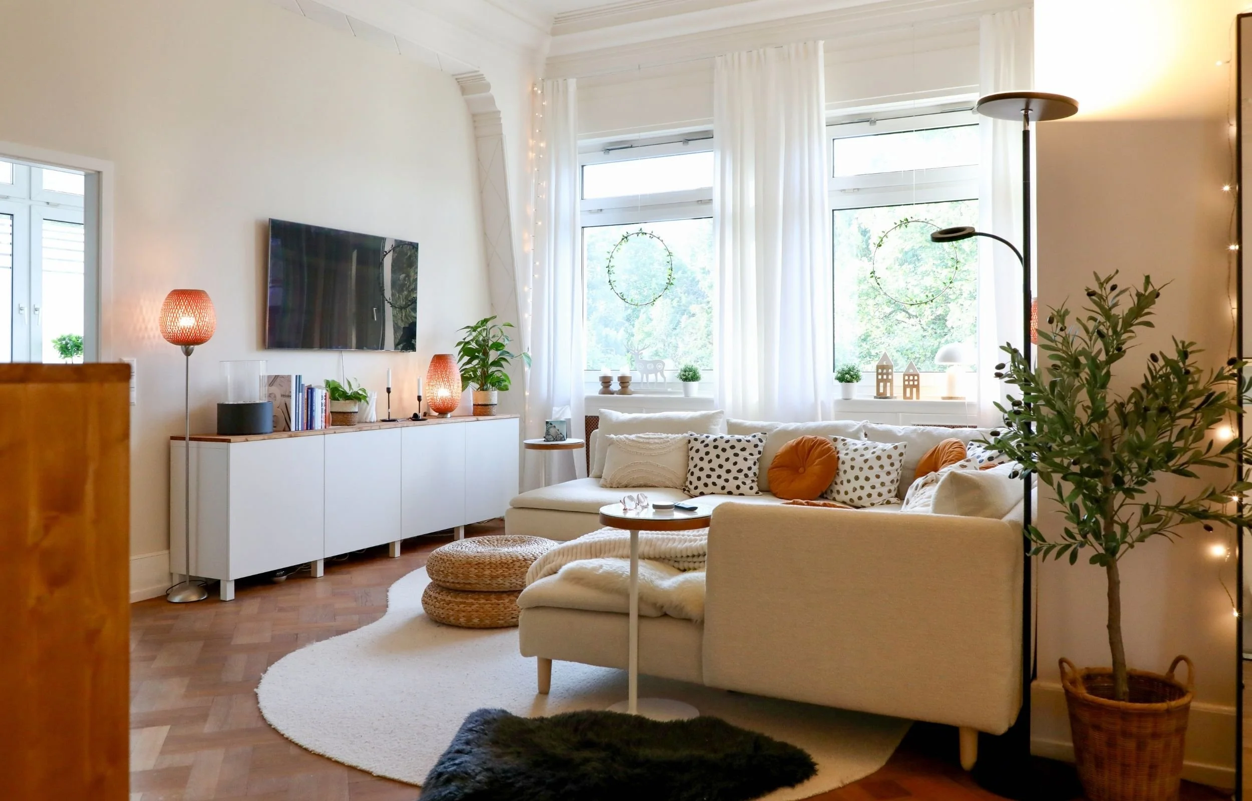 Wohnzimmer mit großem creme Sofa, Sideboard und Fenstern