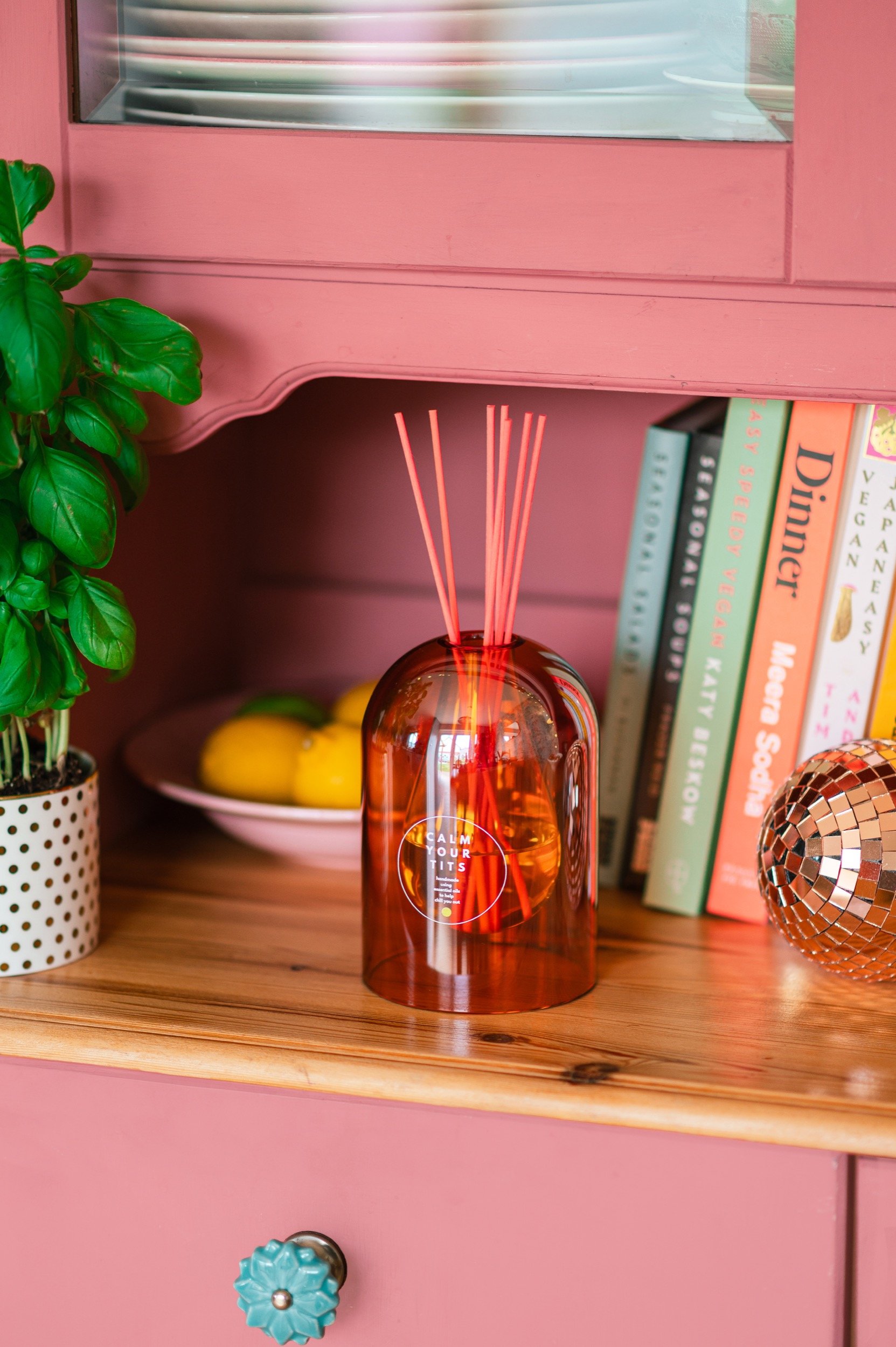a kitchen dresser with diffuser, cookbooks and herbs