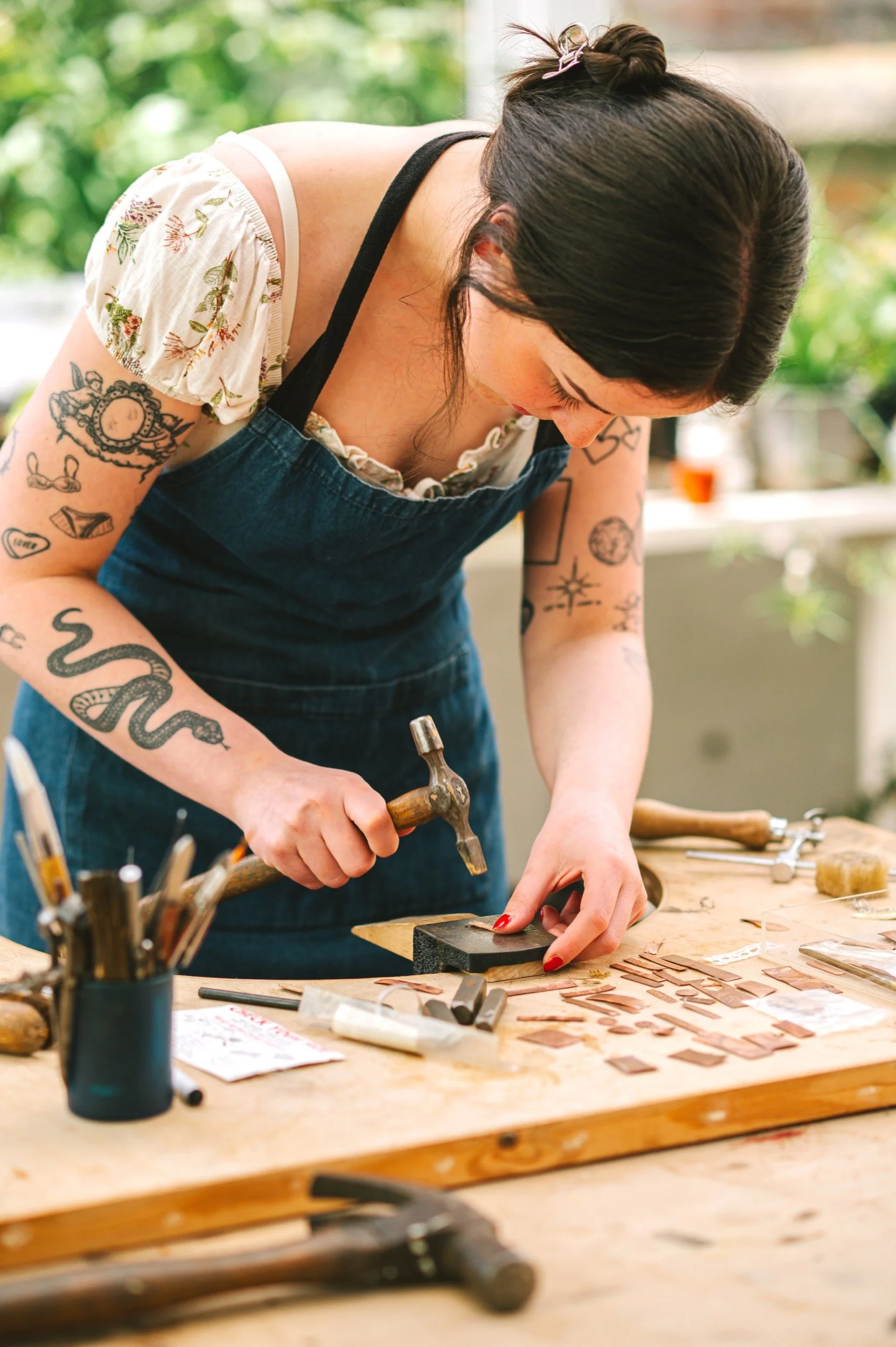 Kiera is hammering a piece of copper during a jewellery workshop
