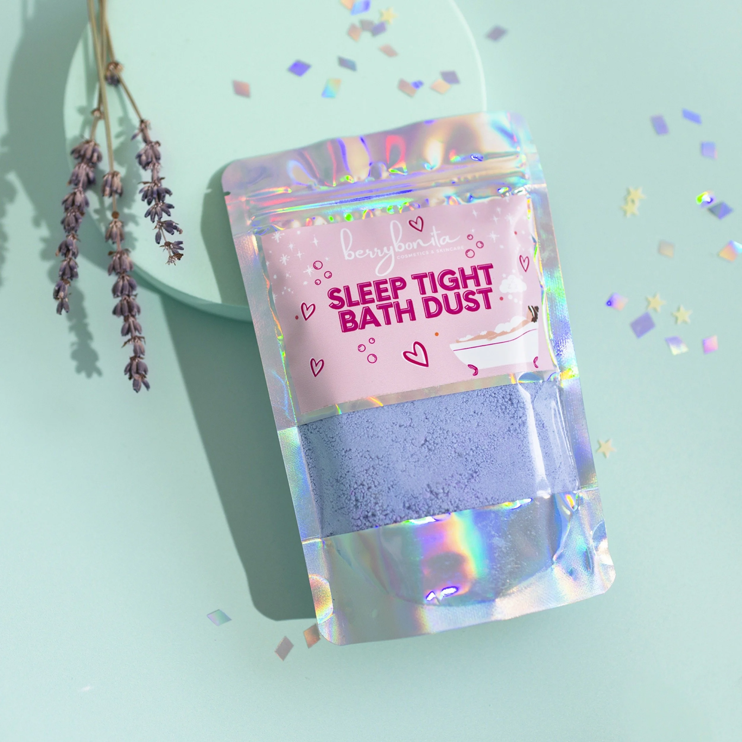 A package of Sleep Tight Bath Dust with purple bath salts, placed on a pastel aqua background with lavender sprigs