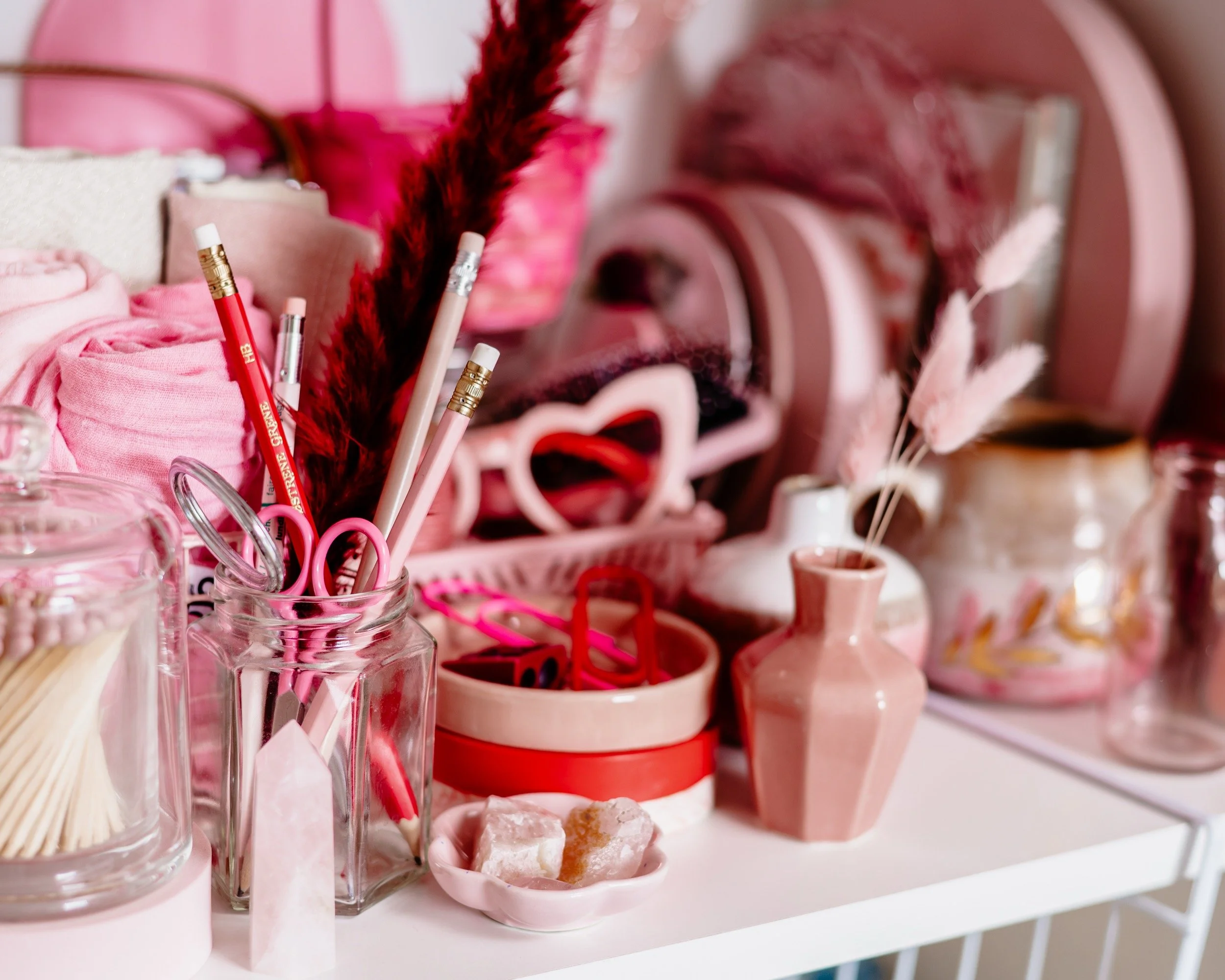 a shelf of pink props including stationery, plates and trinket trays