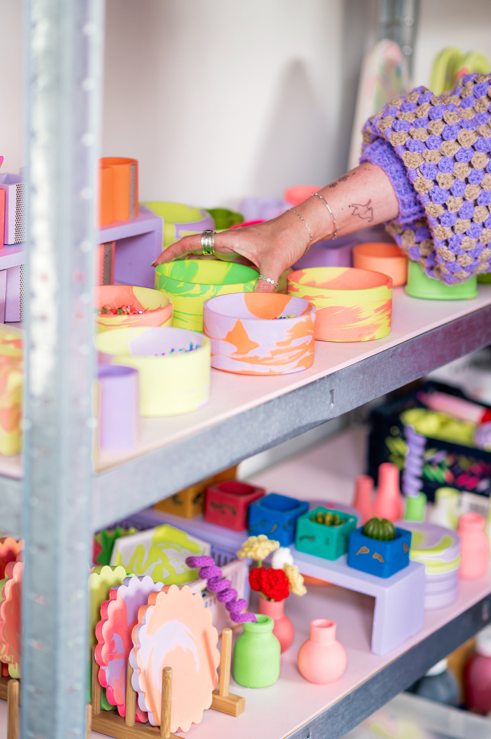 Colourful ceramic planters, vases, and decorative objects on a shelf in a boutique shop.