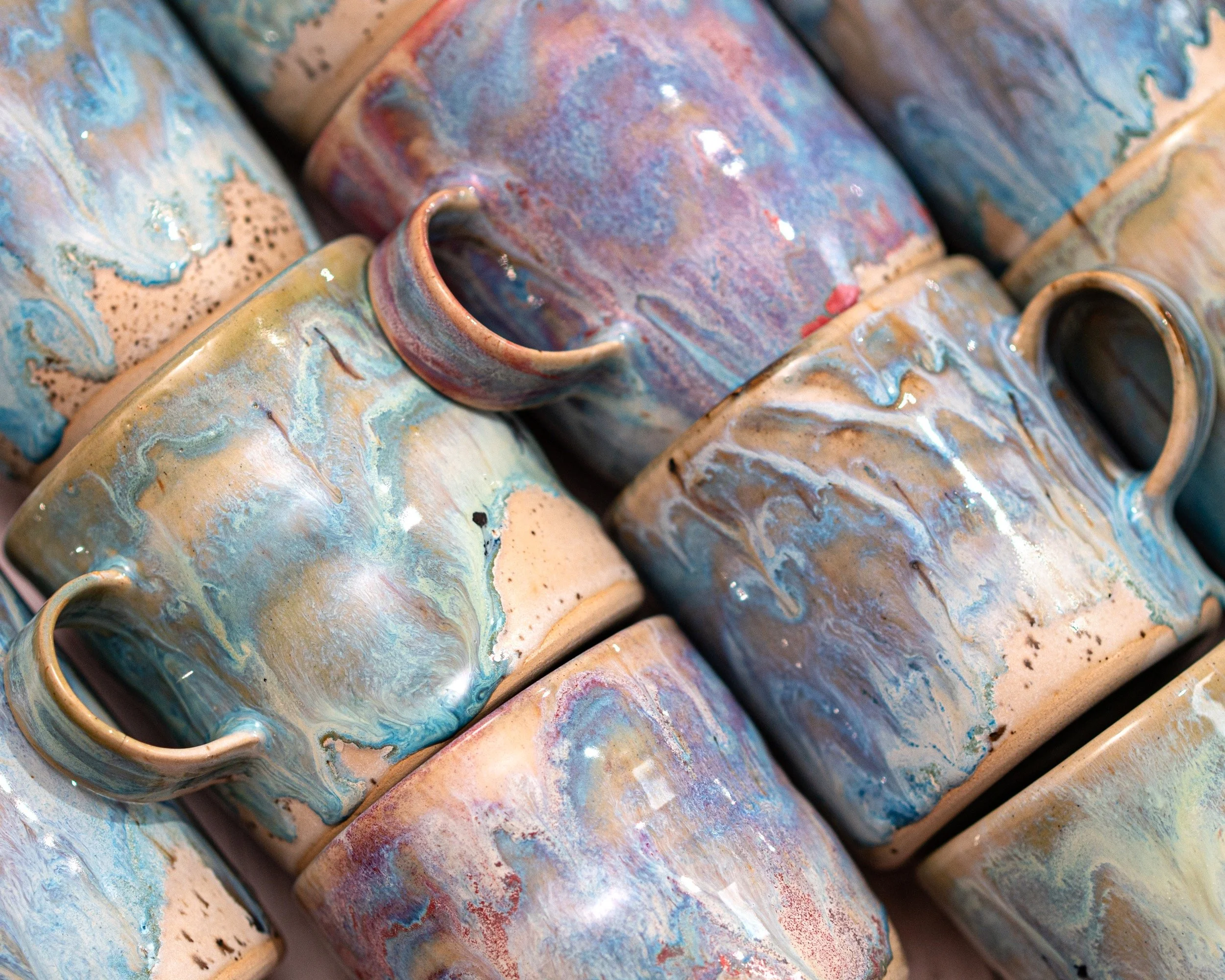 A collection of ceramic mugs with multicolored, marbled glaze patterns