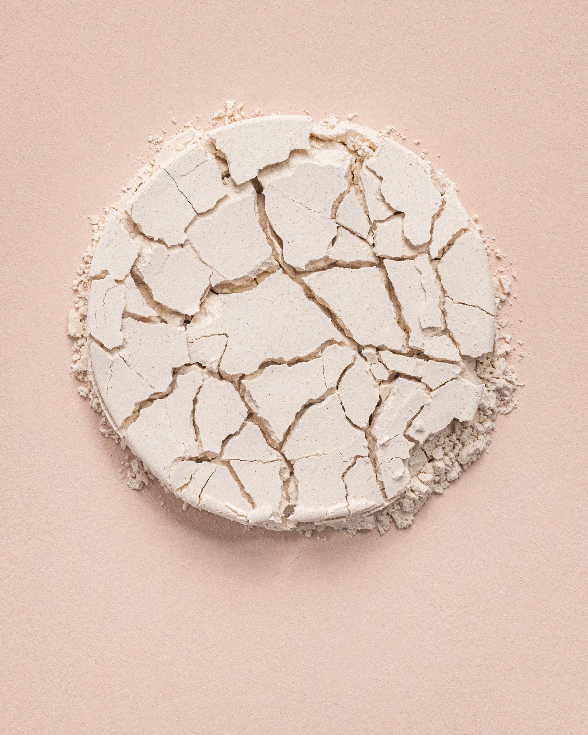 Broken white powdery substance on a pink surface.