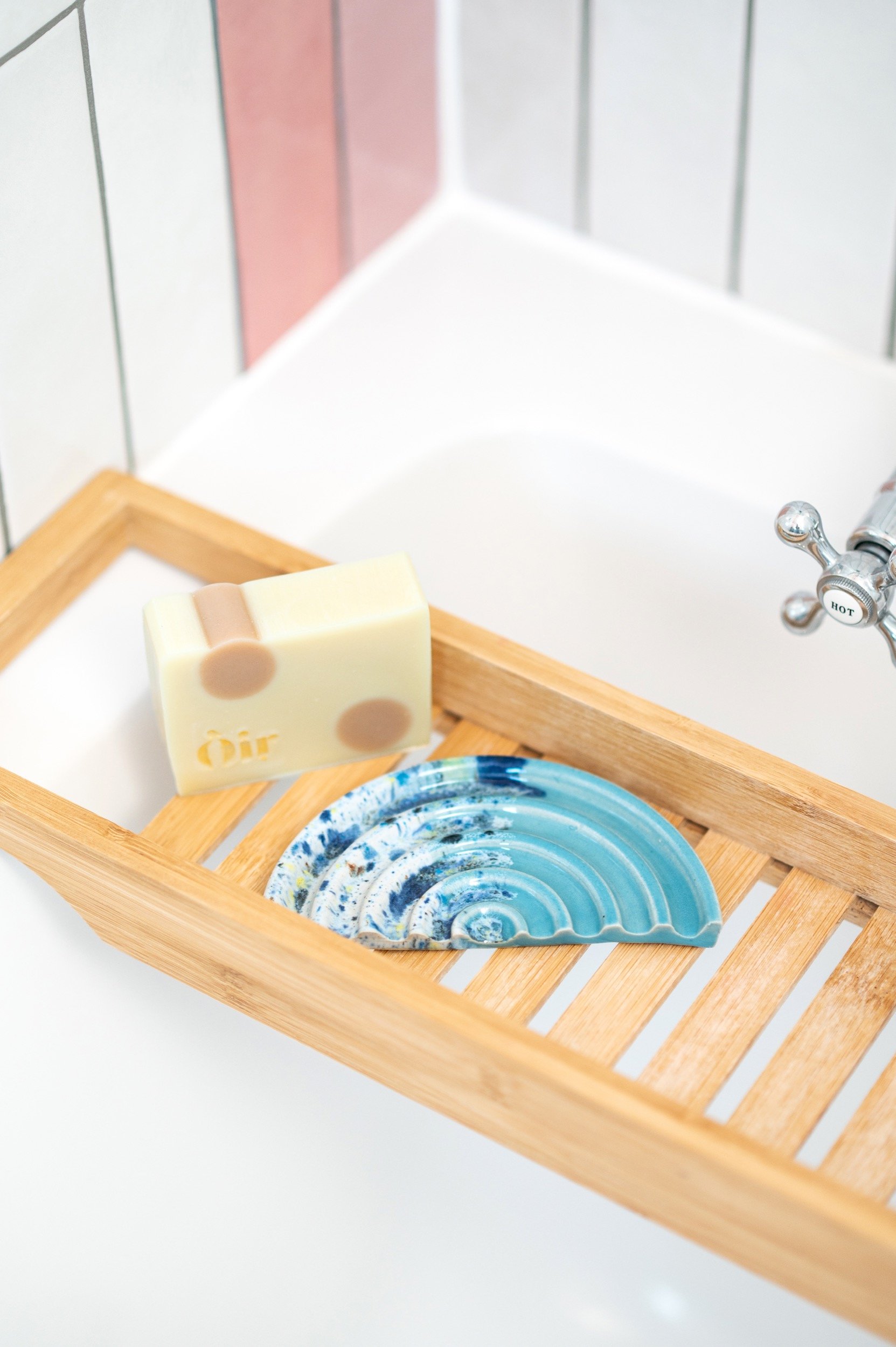 ceramic soap dish sits on a bath tray on the bath