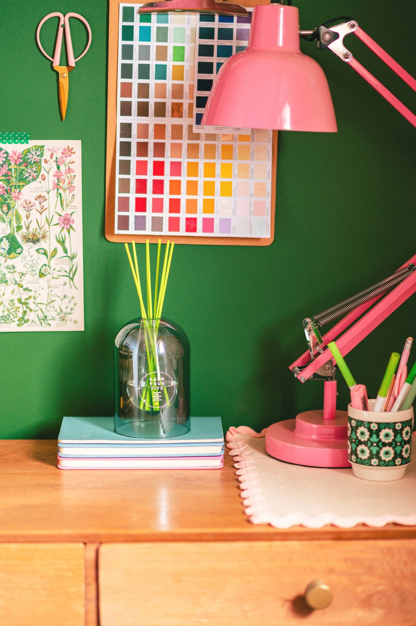 a diffuser sits on a desk with lamp and colour chart
