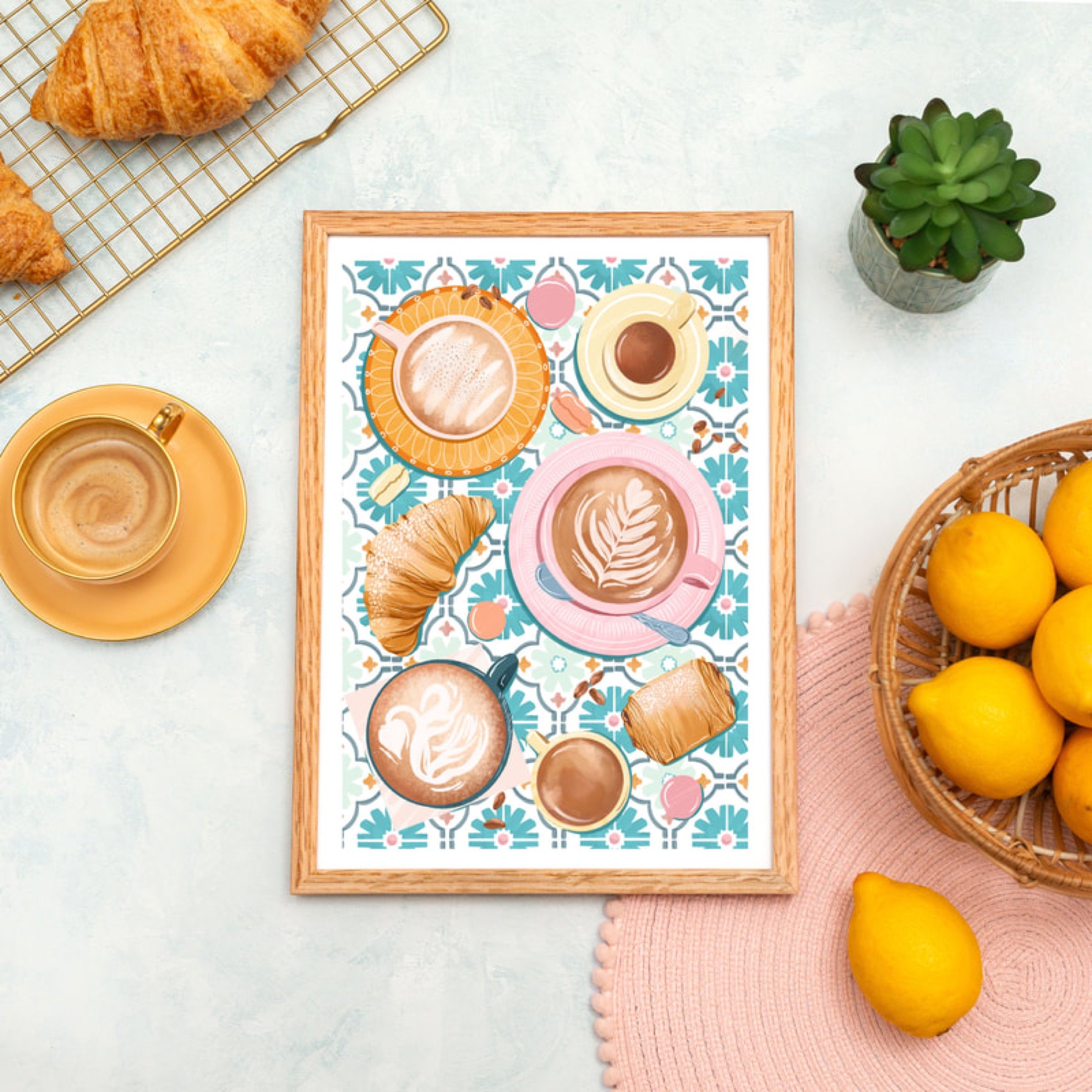 A table with a decorative placemat featuring various coffee cups with latte art, croissants, and small pastries, surrounded by a basket of lemons, a small potted succulent plant, and cups of coffee.