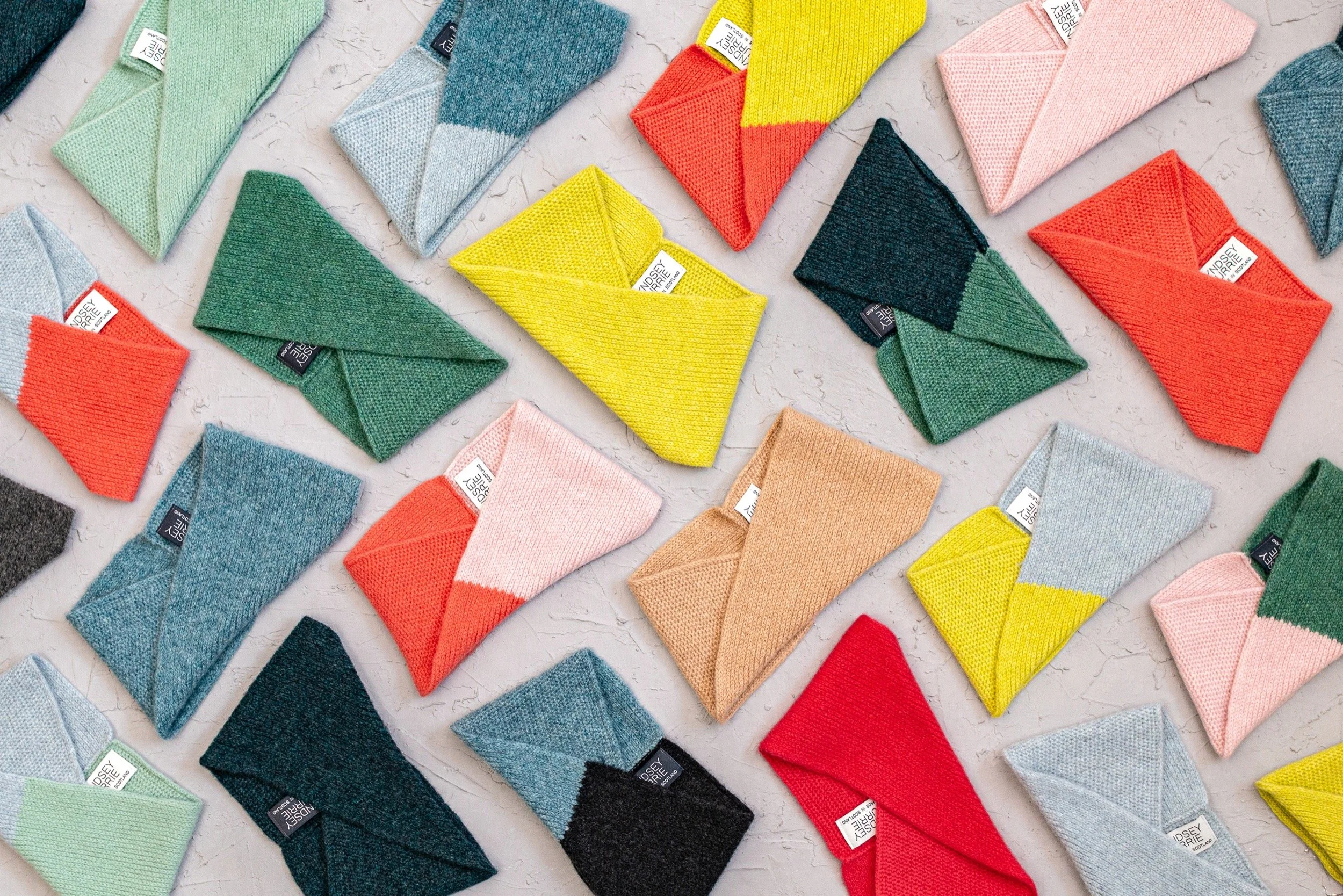 Multiple colourful headbands arranged on a surface, featuring various colours such as green, yellow, pink, blue, red, peach, and black.