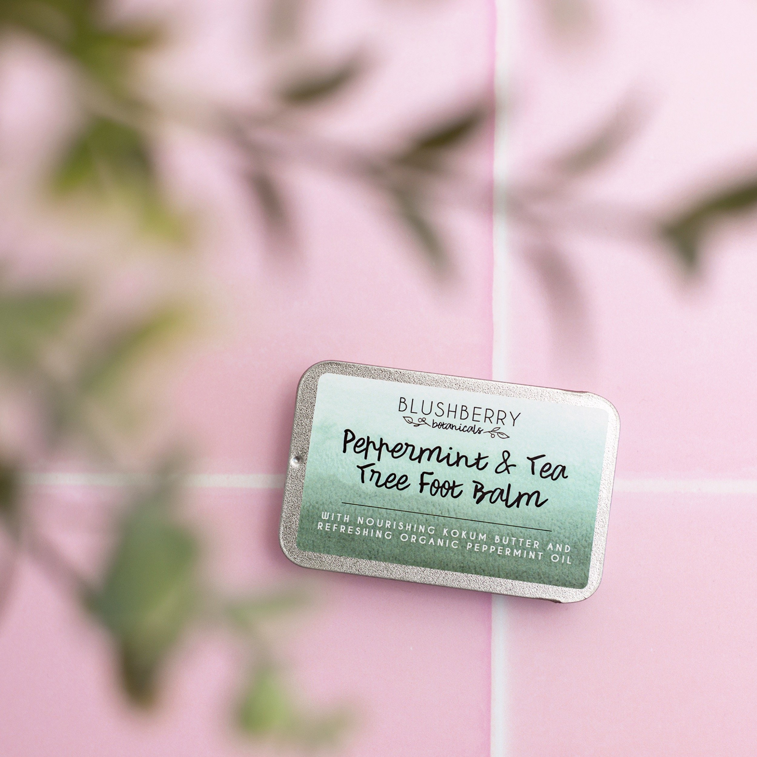 foot balm sits on pink tiles with soft focus branch in front