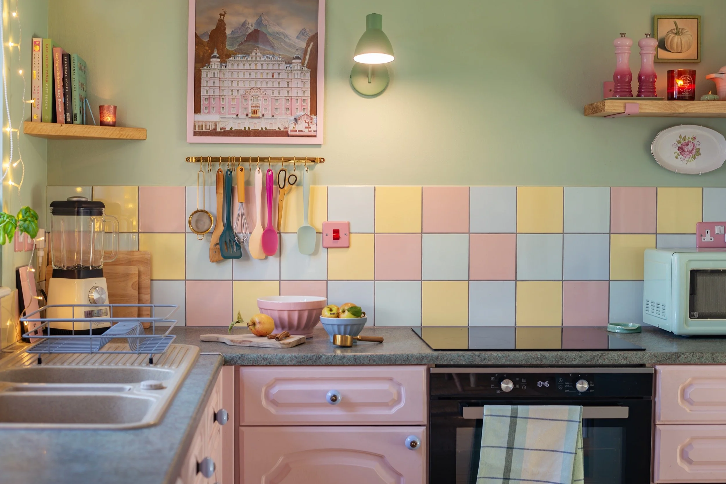 a colourful kitchen scene with pink cabinets and pastel tiles