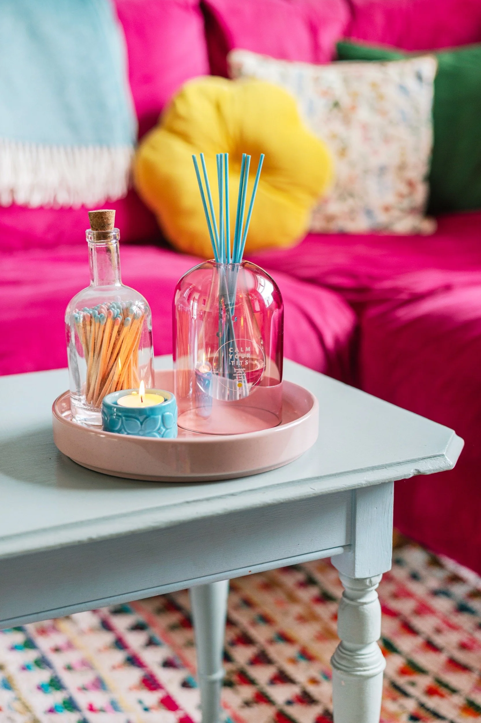 a diffuser sits on a tray on the coffee table in front of a colourful sofa