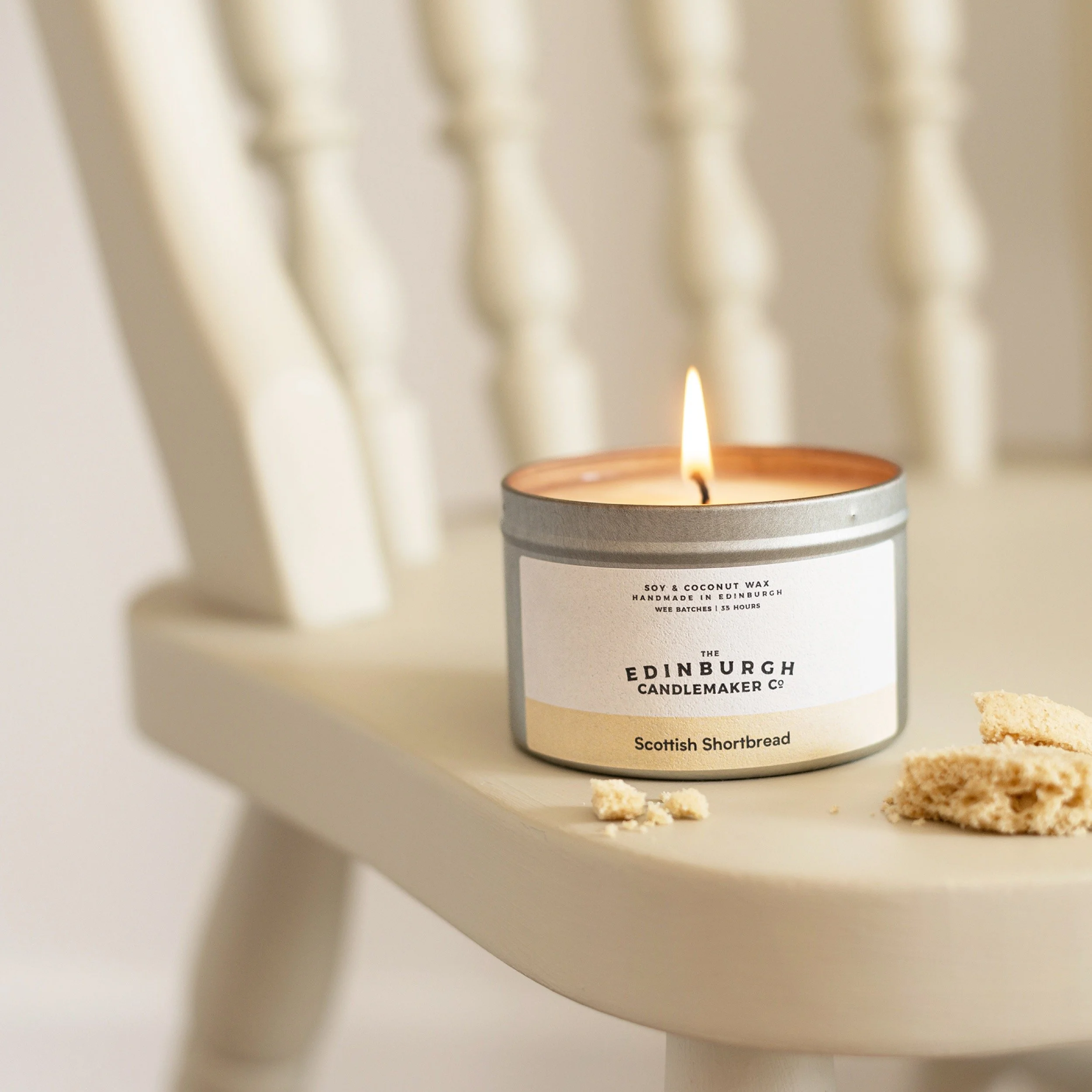 a scottish shortbread candle sits on a cream coloured chair with crumbled shortbread