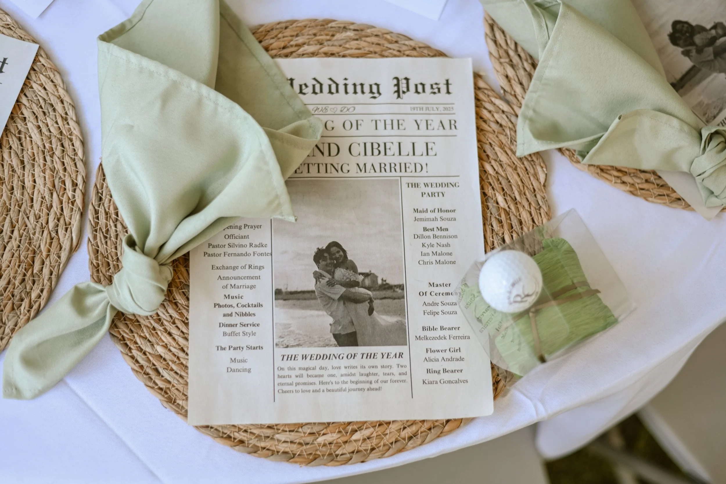 A wedding program on a table, decorated with a light green ribbon, placed on a woven placemat, featuring details of a wedding event and a vintage black and white photo of a couple embracing.