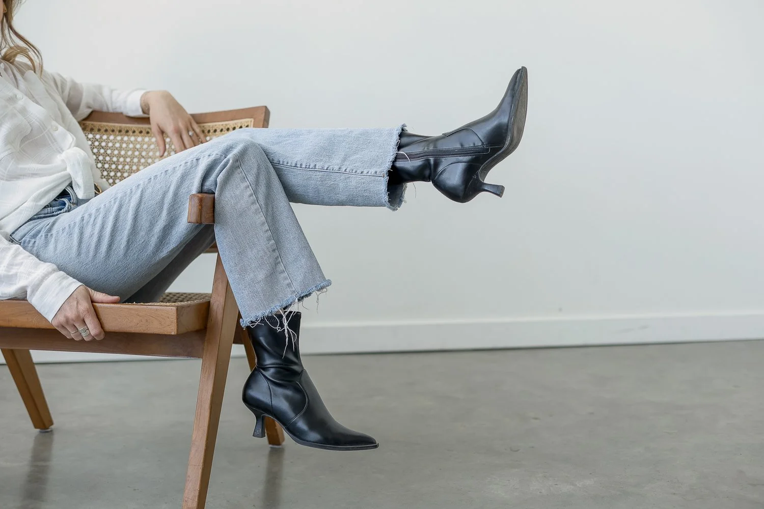 woman sitting on chair in jeans with black boots kicked out
