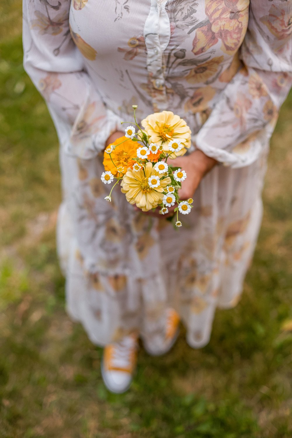 woman in dress holding a small bouquet of fresh yellow flowers