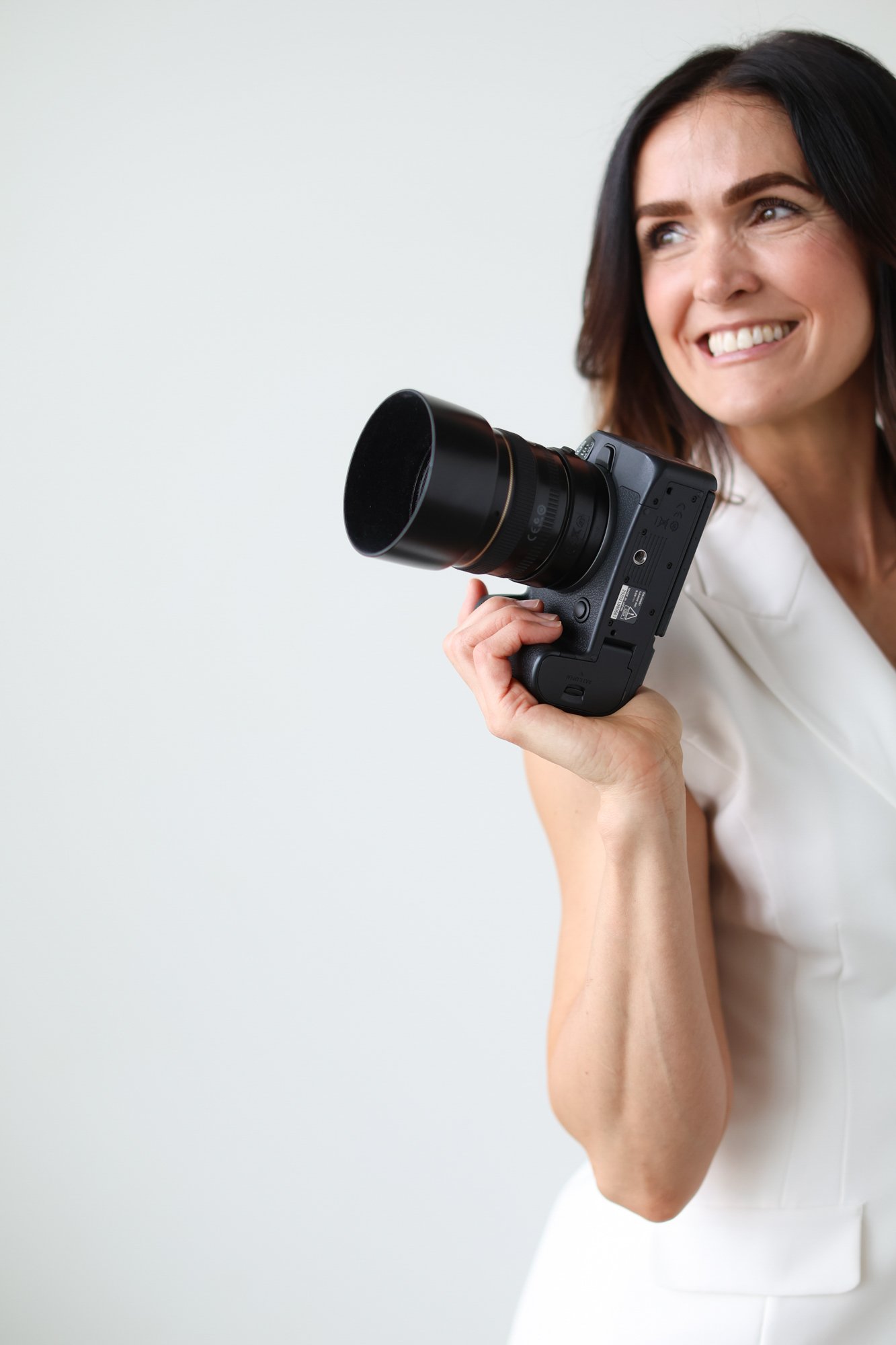 photo of a woman smiling and holding a camera, half the body cut off strategically
