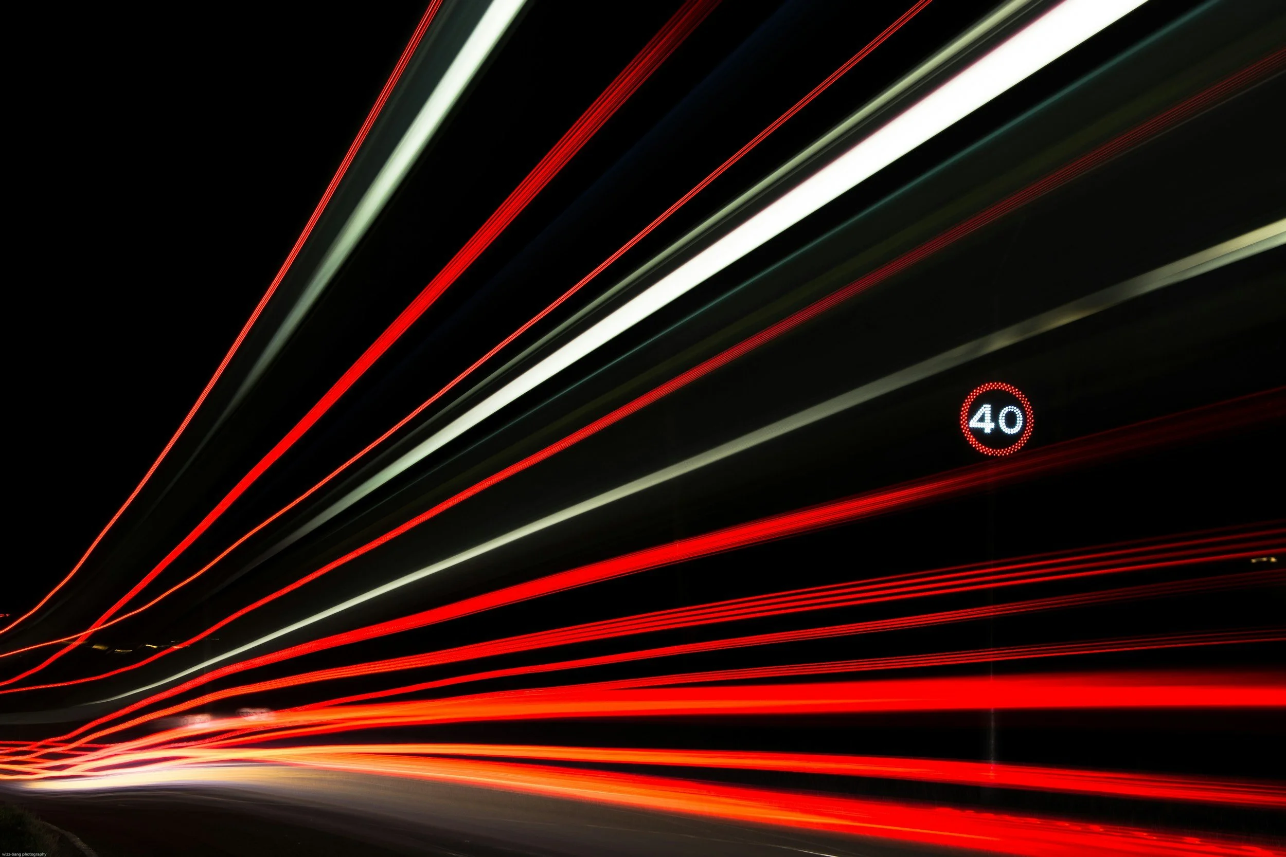 Light trails from moving vehicles on a highway at night, with a speed limit sign showing 40 mph.