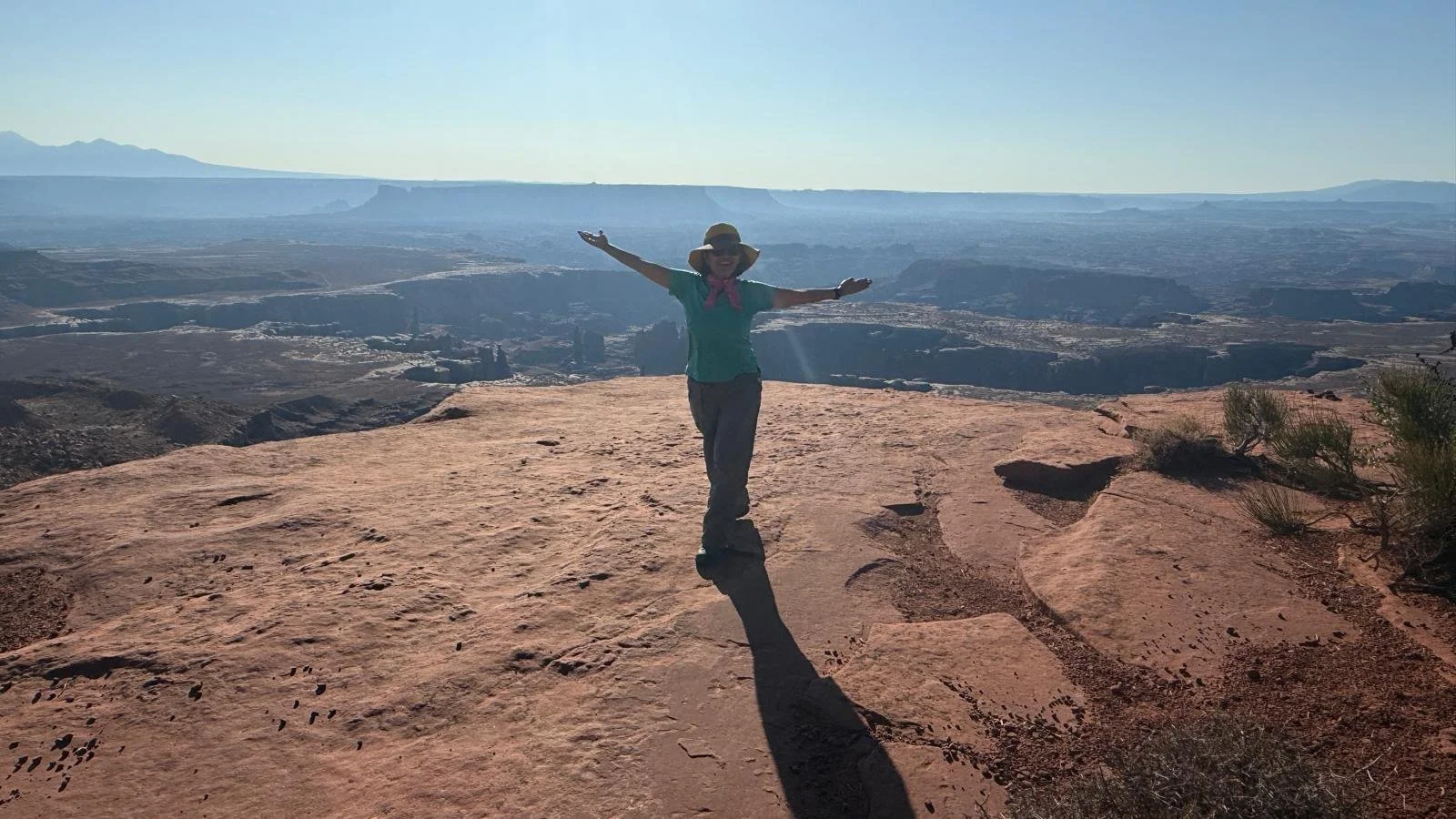Anu Arora standing on a large outcropping in Arches Park with arms outstretched