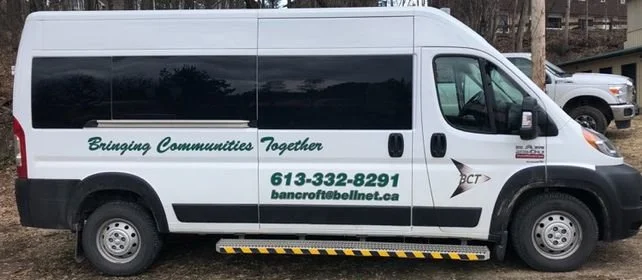 A white van with green lettering that reads 'Bringing Communities Together,' a phone number, and an email address.
