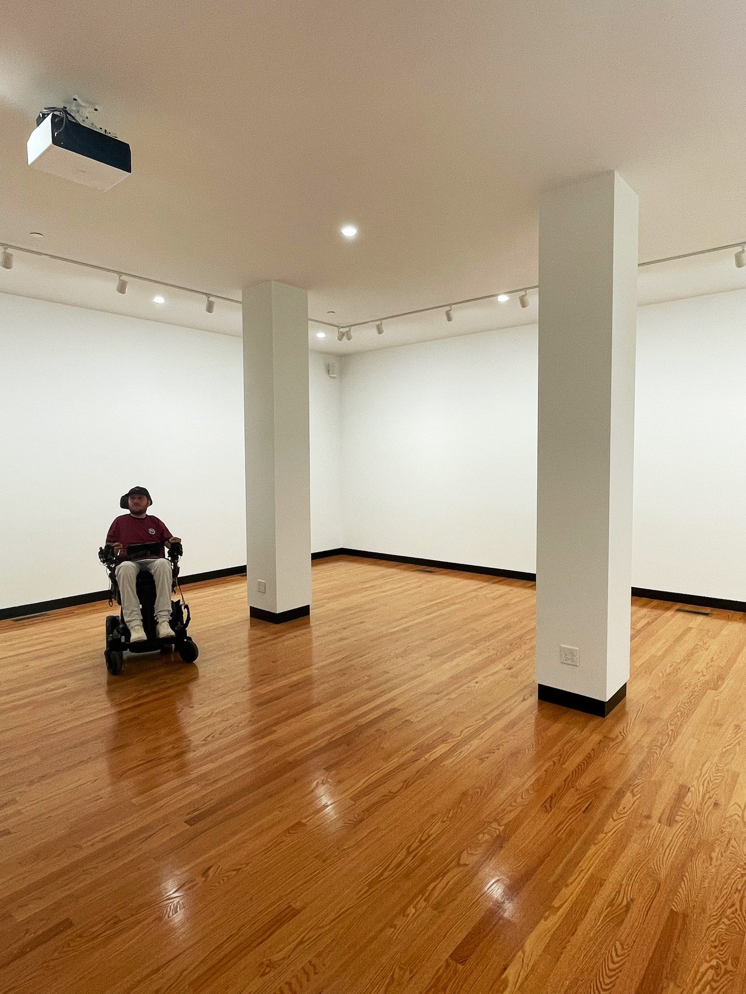 Artist and owner Archer Senft in power wheelchair inside Archer Hawkins Gallery exhibition space.