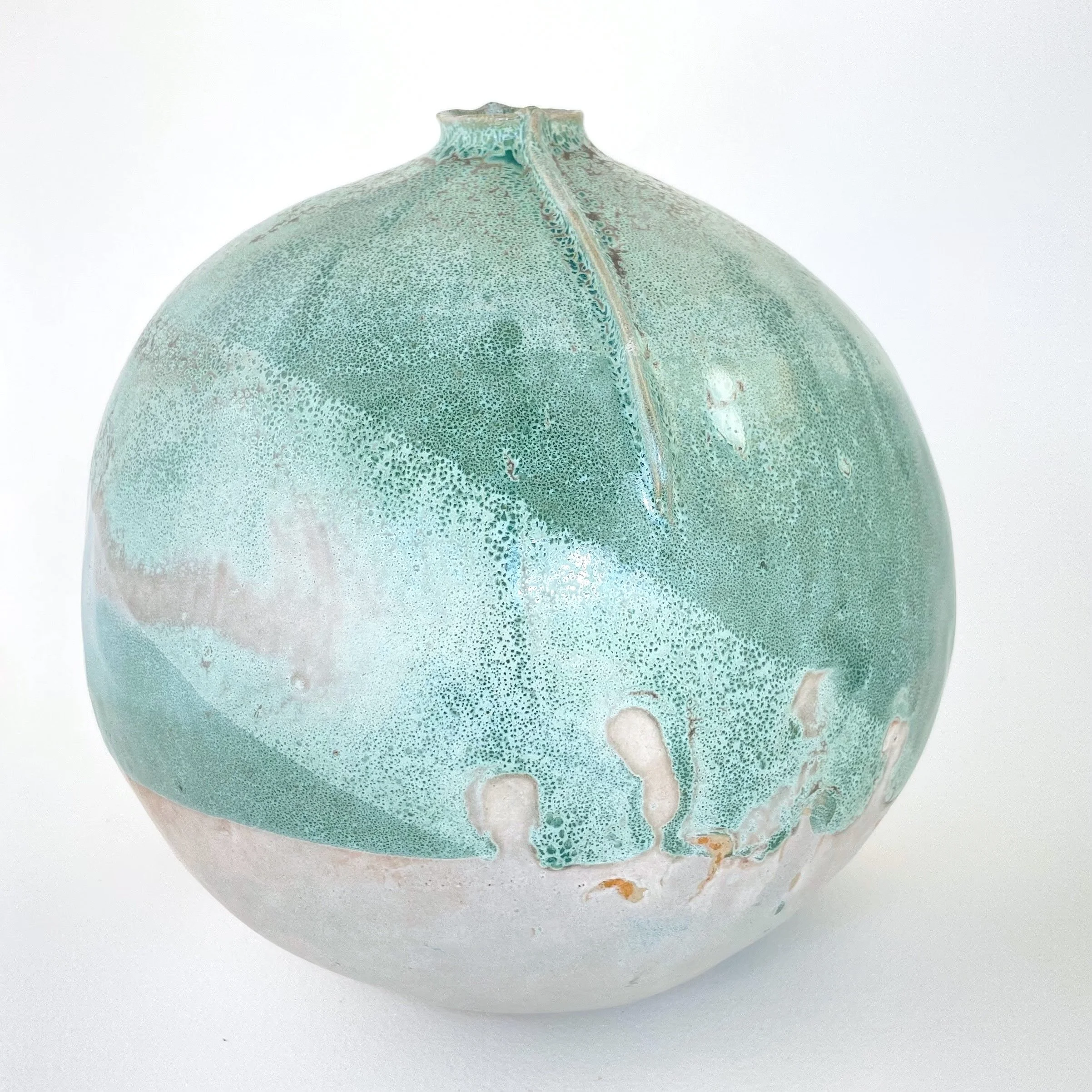 A round ceramic vase with a textured, light aquamarine glaze and a small opening at the top, set against a plain white background.